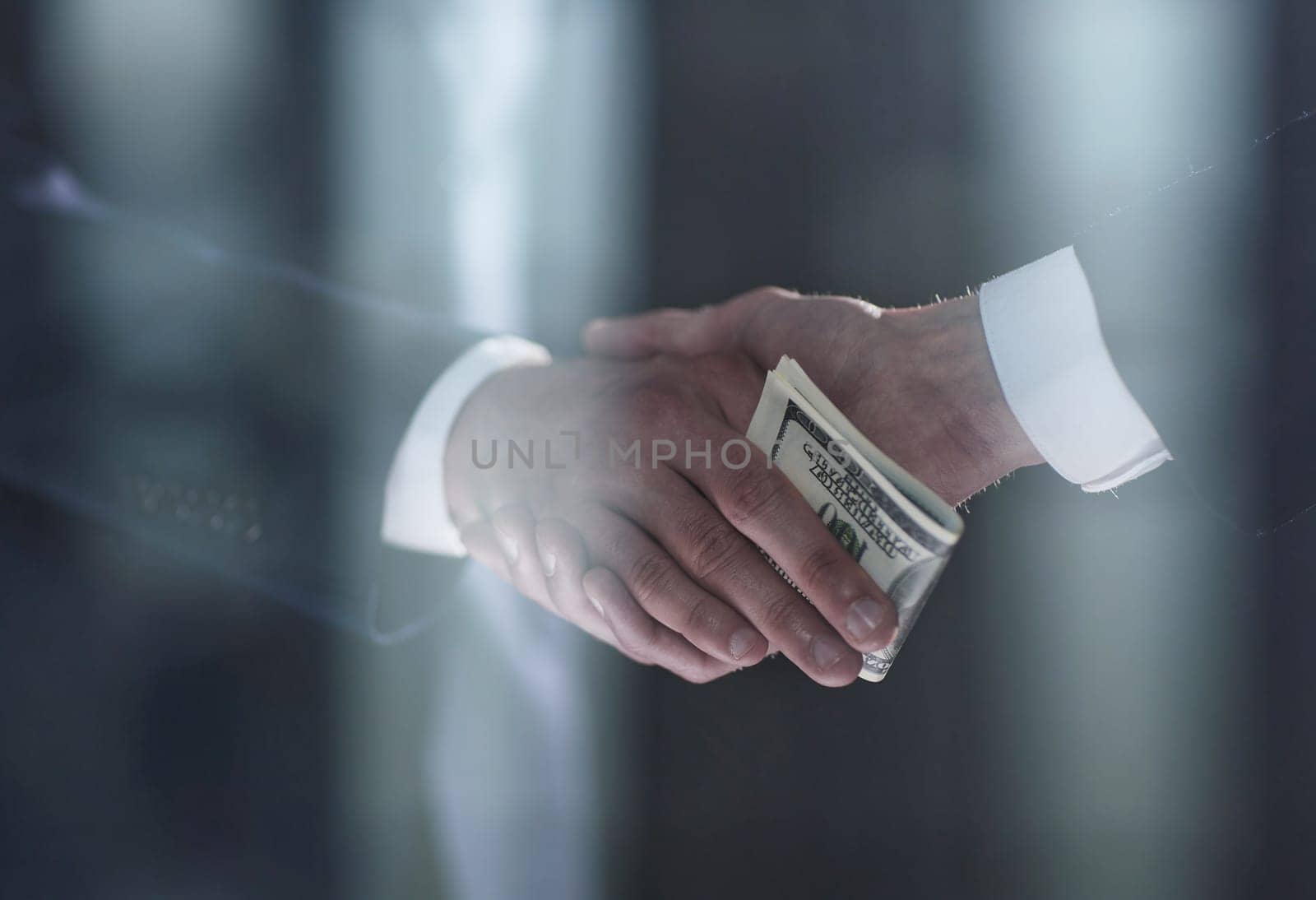 Handshake with the transfer of money on a black background
