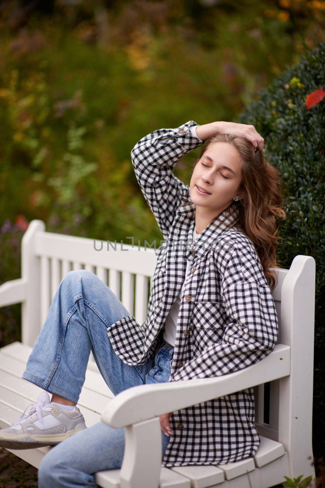 Beautiful teen blonde girl sits on a bench in an autumn park . attractive young smiling girl sitting on a bench in an autumn park by Andrii_Ko