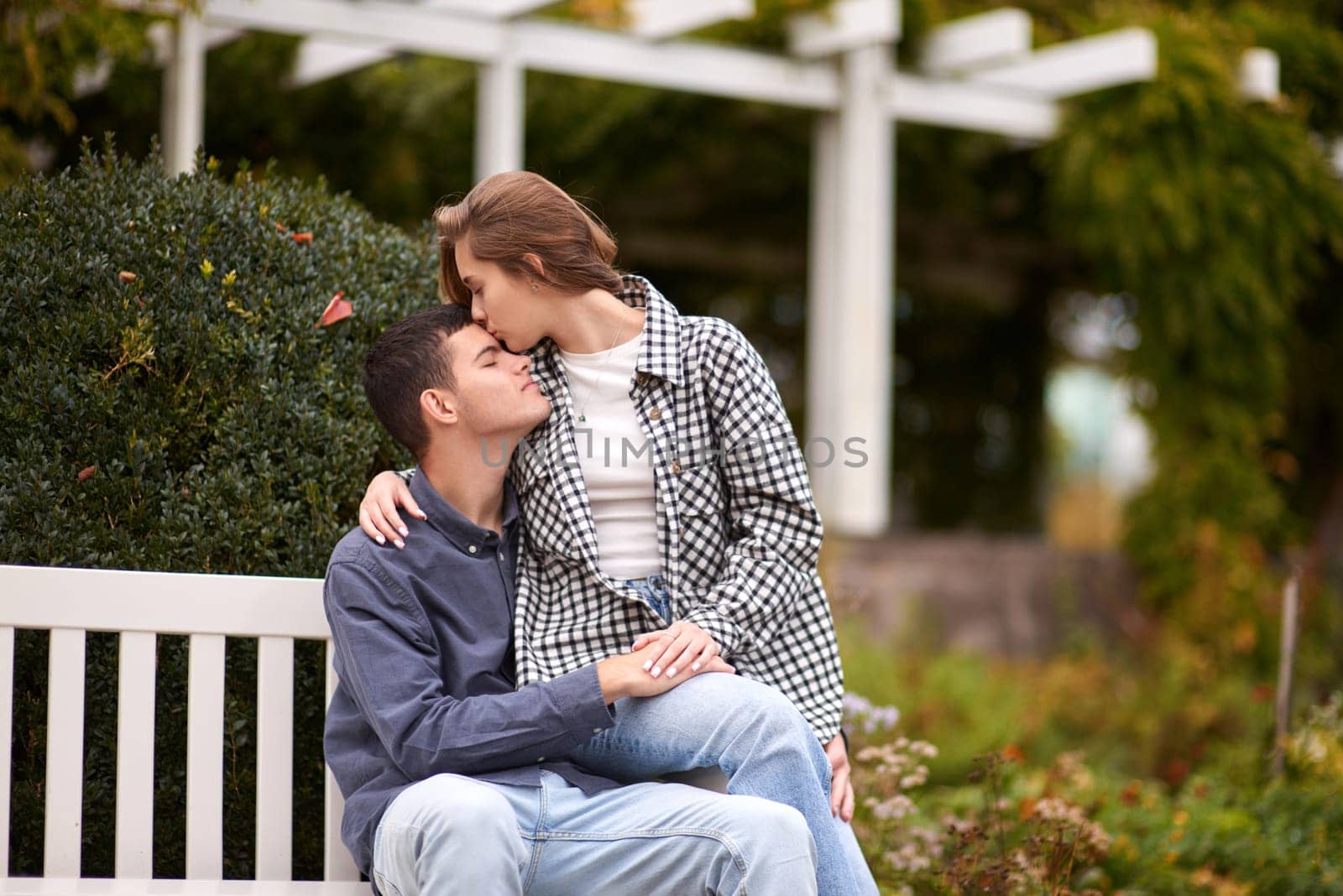 Autumn Romance: Young Couple Embracing and Kissing on Park Bench. Young couple kissing and rejoices at the lake. lovely young couple kissing outdoors in autumn. Embraced in Autumn's Warmth: Couple's Kiss on Park Bench. Loving couple walking in nature. Autumn mood. Happy man and woman hugging and kissing in autumn. Love. Fashionable couple outdoors. Fashion, people and lifestyle. Stylish couple in autumn outfit. by Andrii_Ko