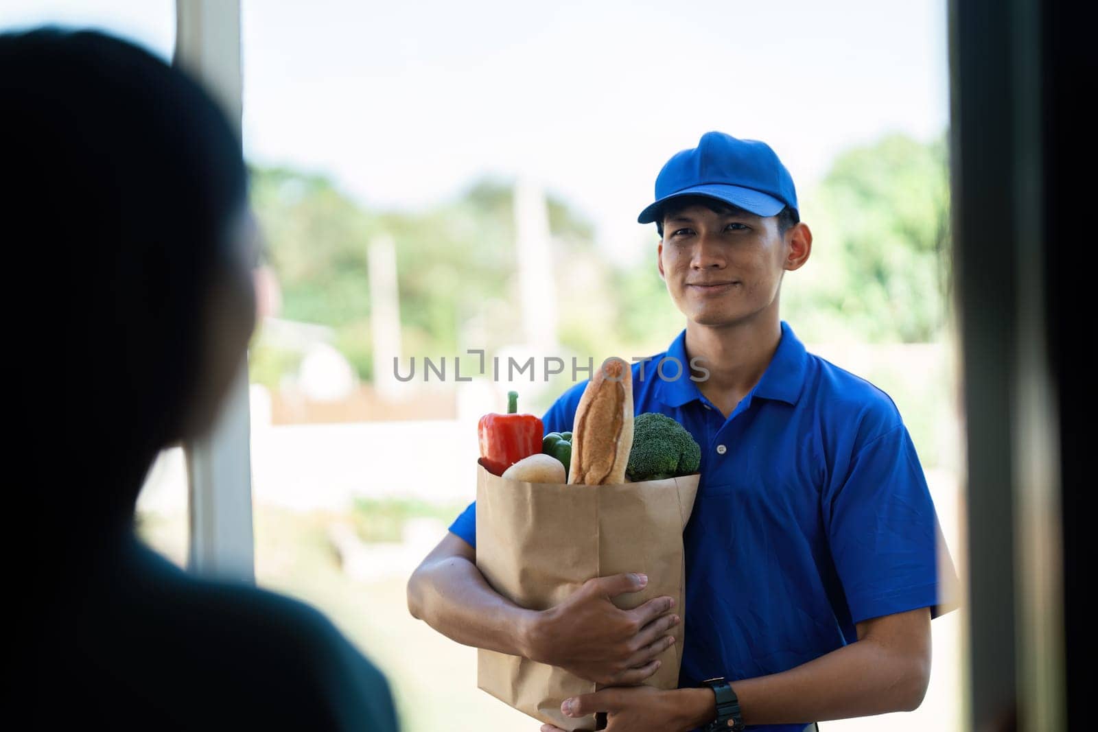 Asian young delivery man delivering package to female customer at home by itchaznong