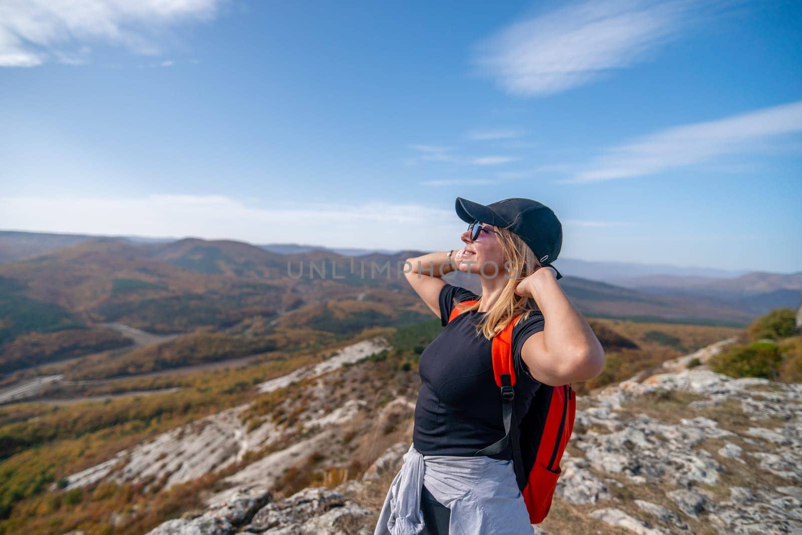 woman on mountain peak looking in beautiful mountain valley in autumn. Landscape with sporty young woman, blu sky in fall. Hiking. Nature.