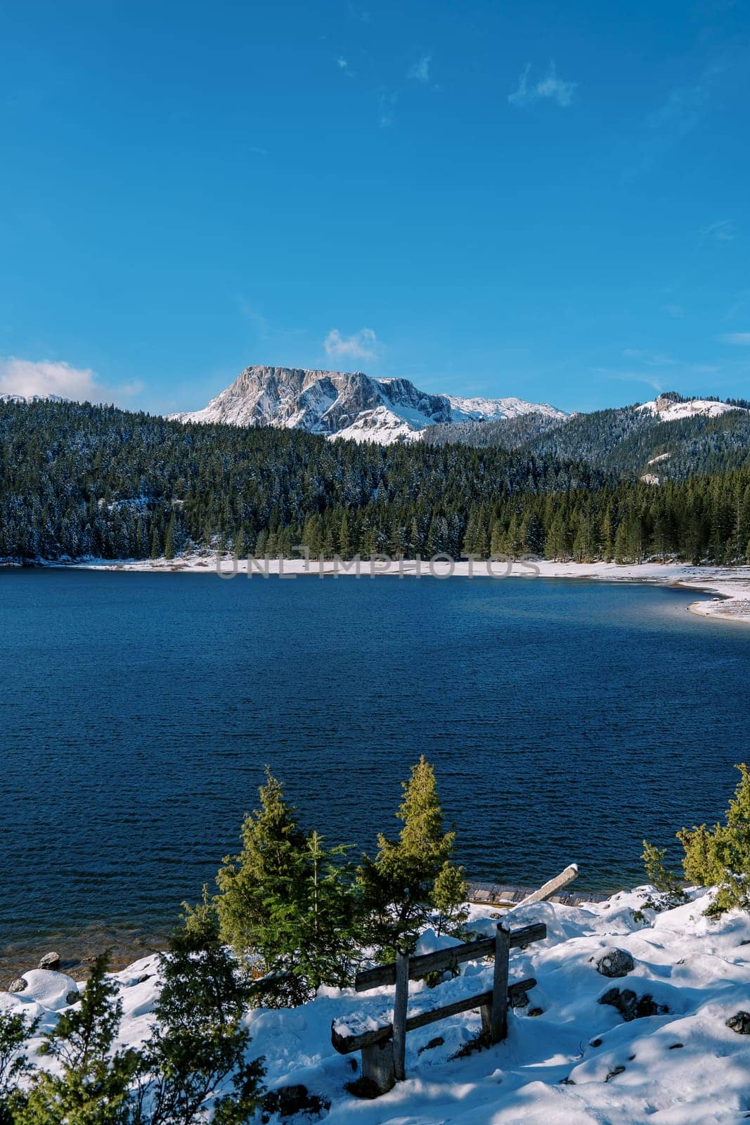 Wooden bench on the snowy shore of the Black Lake. Durmitor National Park, Montenegro. High quality photo