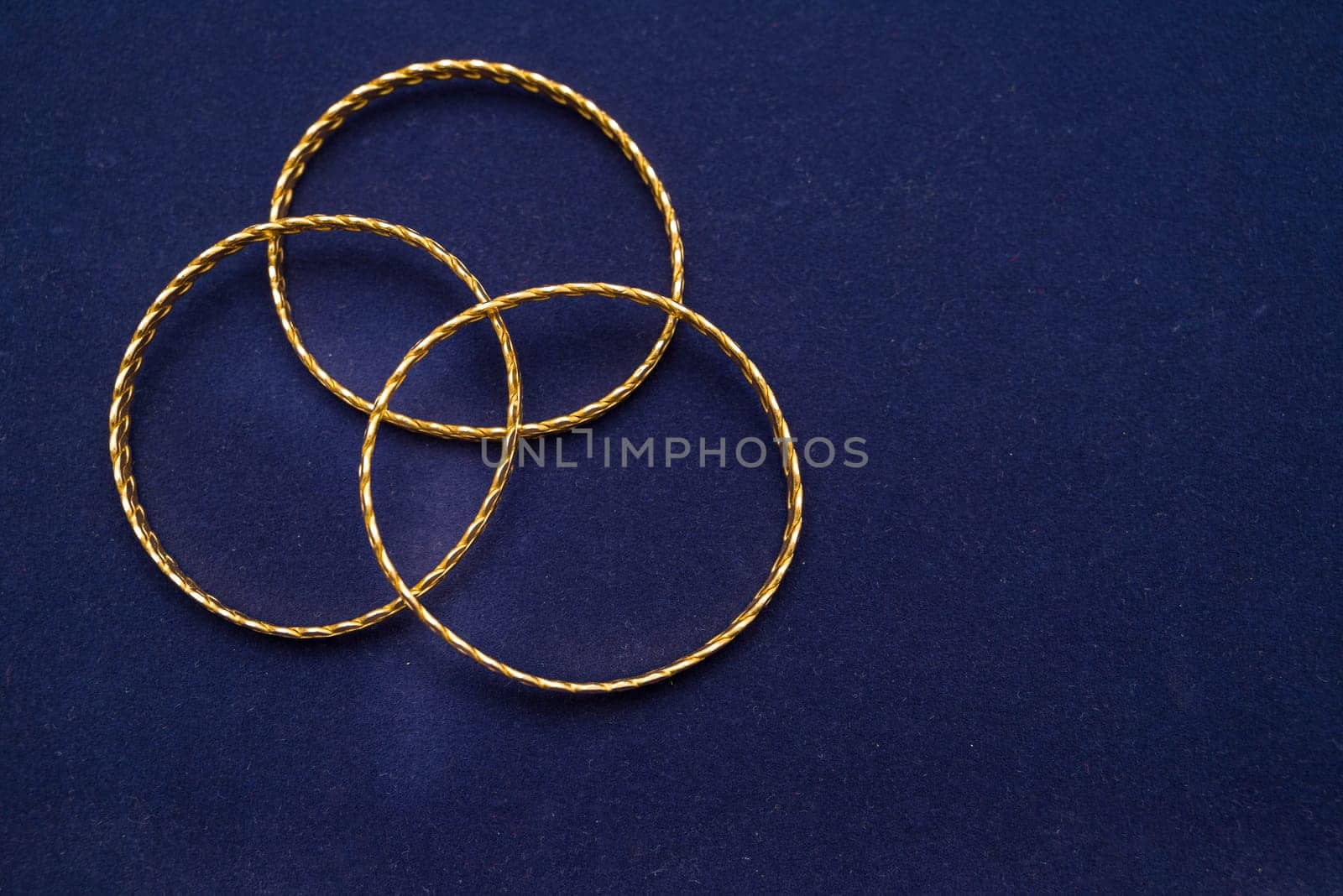 24k (24 carat) Turkish gold twist bracelet standing in a heap on a dark blue background in the gold store by Sonat