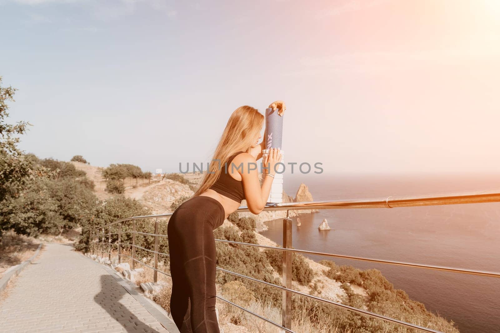 Fitness woman sea. Outdoor workout on yoga mat roller in park near to ocean beach. Female fitness pilates yoga routine concept. Healthy lifestyle. Happy fit woman exercising with rubber band in park. by panophotograph