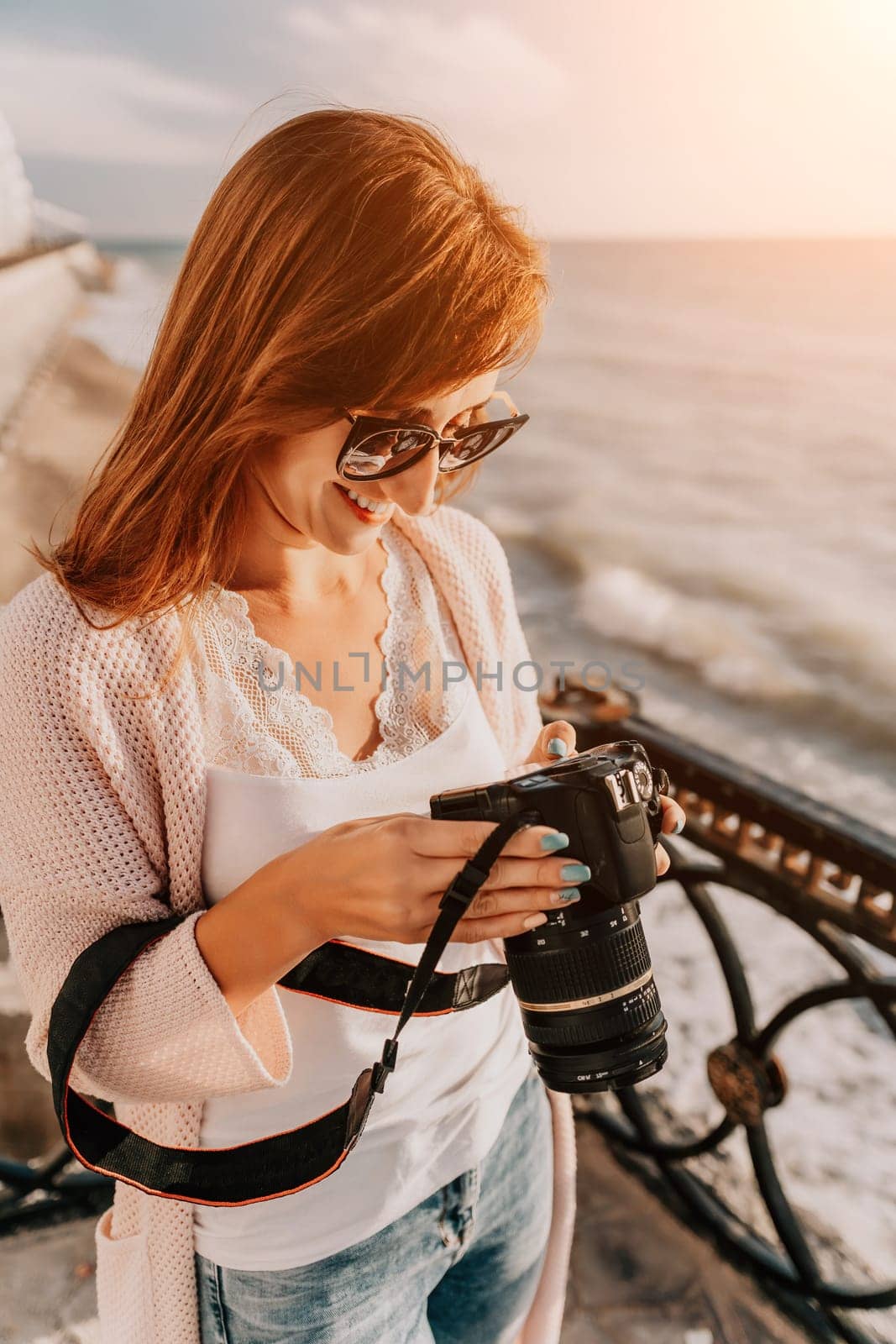 Woman summer travel sea. Happy tourist enjoy taking picture outdoors for memories. Carefree woman traveler posing on beach at sea on sunset, sharing travel adventure journey. Holiday vacation concept. by panophotograph