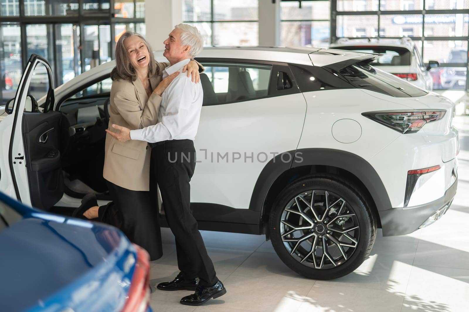 Mature Caucasian couple hugging with happiness while buying a new car. by mrwed54