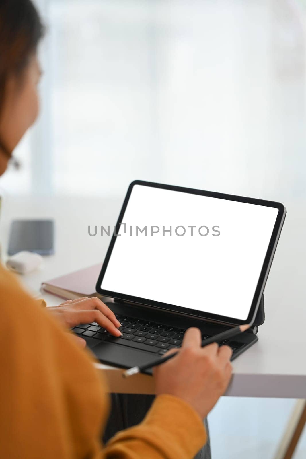 Side view female freelancer working on digital tablet at white desk. Blank screen foe your advertising
