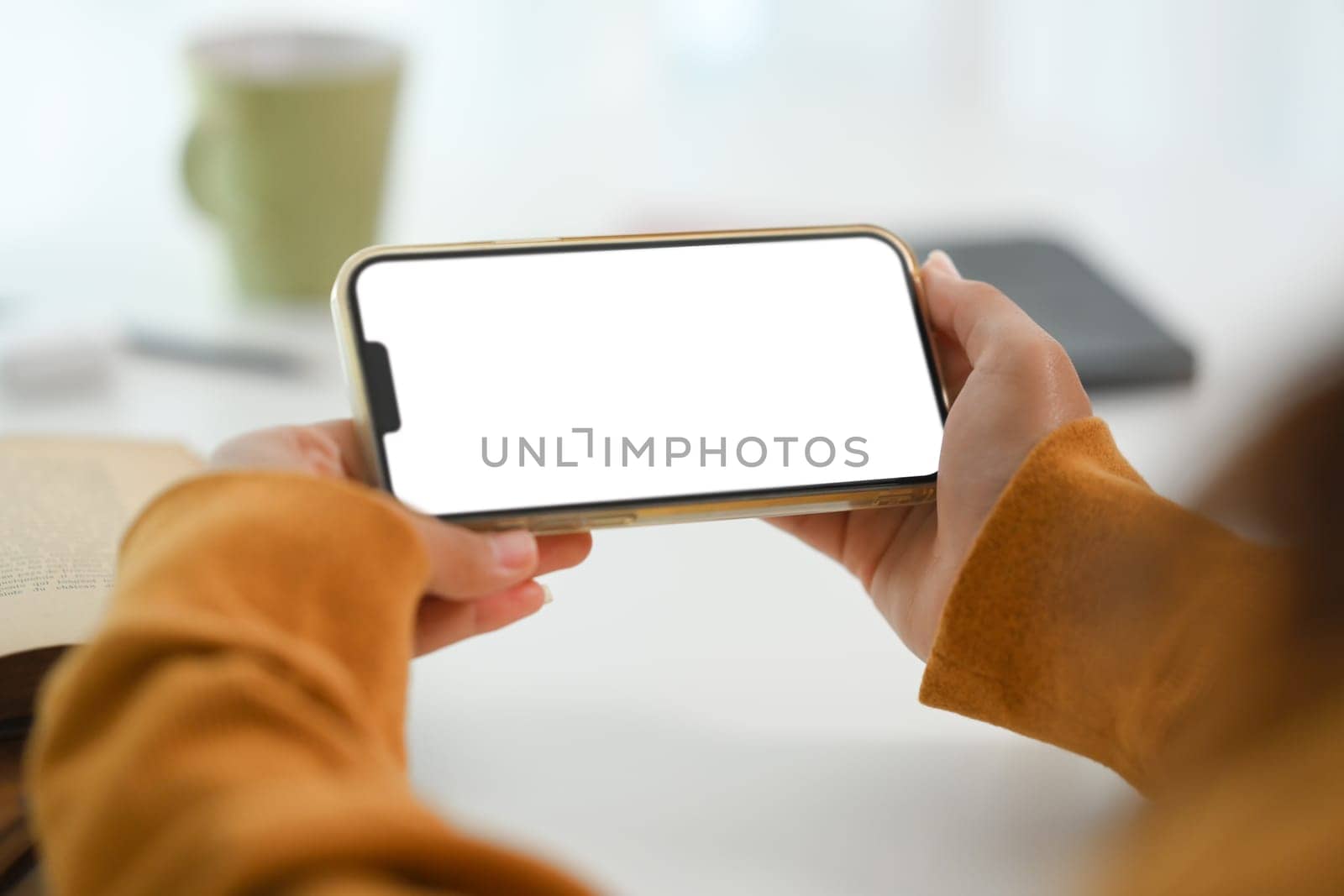 Hands holding a smartphone horizontally with blank screen. Closeup view. by prathanchorruangsak