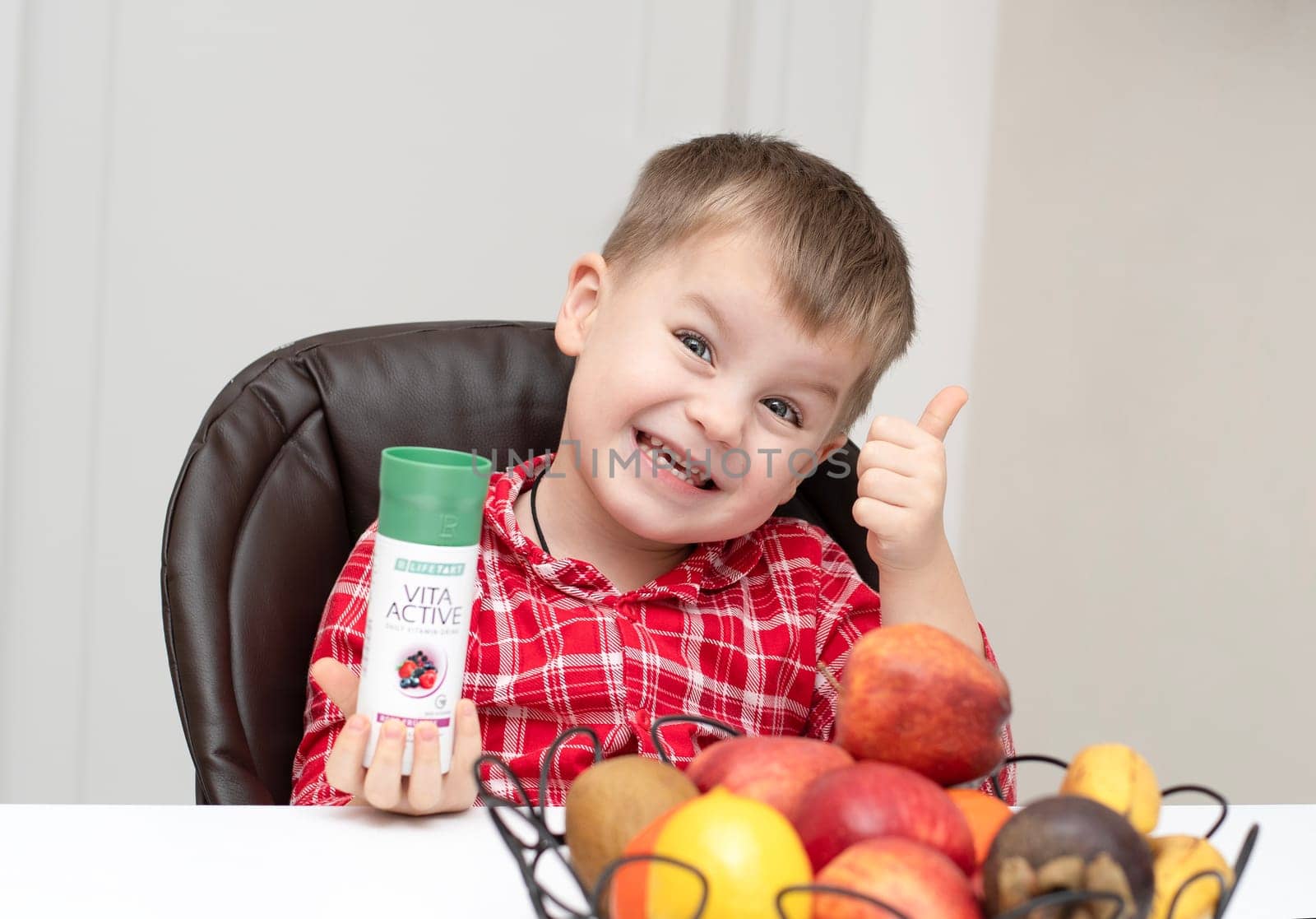 Dnepr, Ukraine - January 03,2024: a small handsome boy is sitting at a table with products from the cosmetic company LR Health and Beauty, vitamins, probiotic, colostrum. Close-up