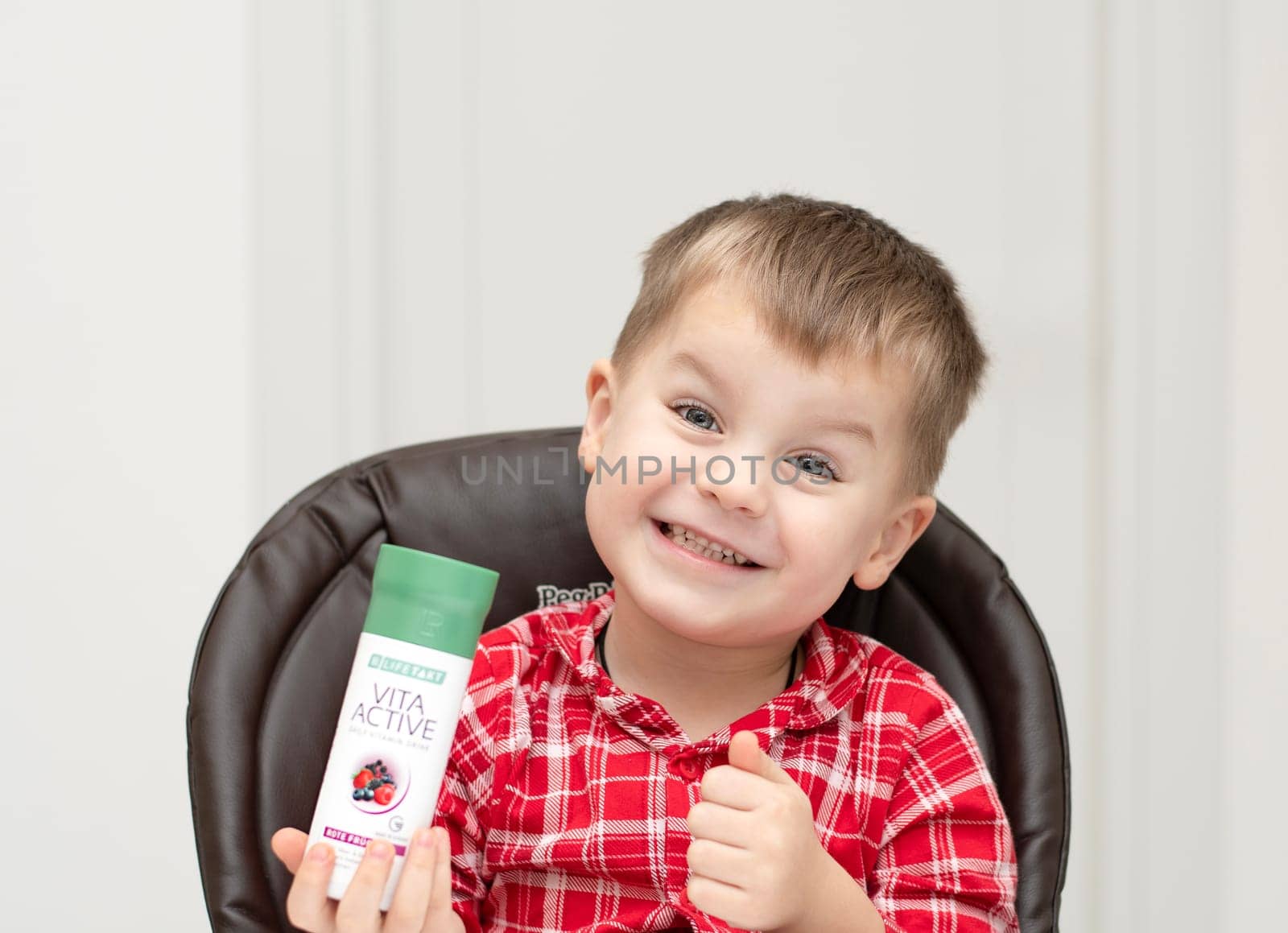 Dnepr, Ukraine - January 03,2024: a small handsome boy is sitting at a table with products from the cosmetic company LR Health and Beauty, vitamins, probiotic, colostrum. Close-up