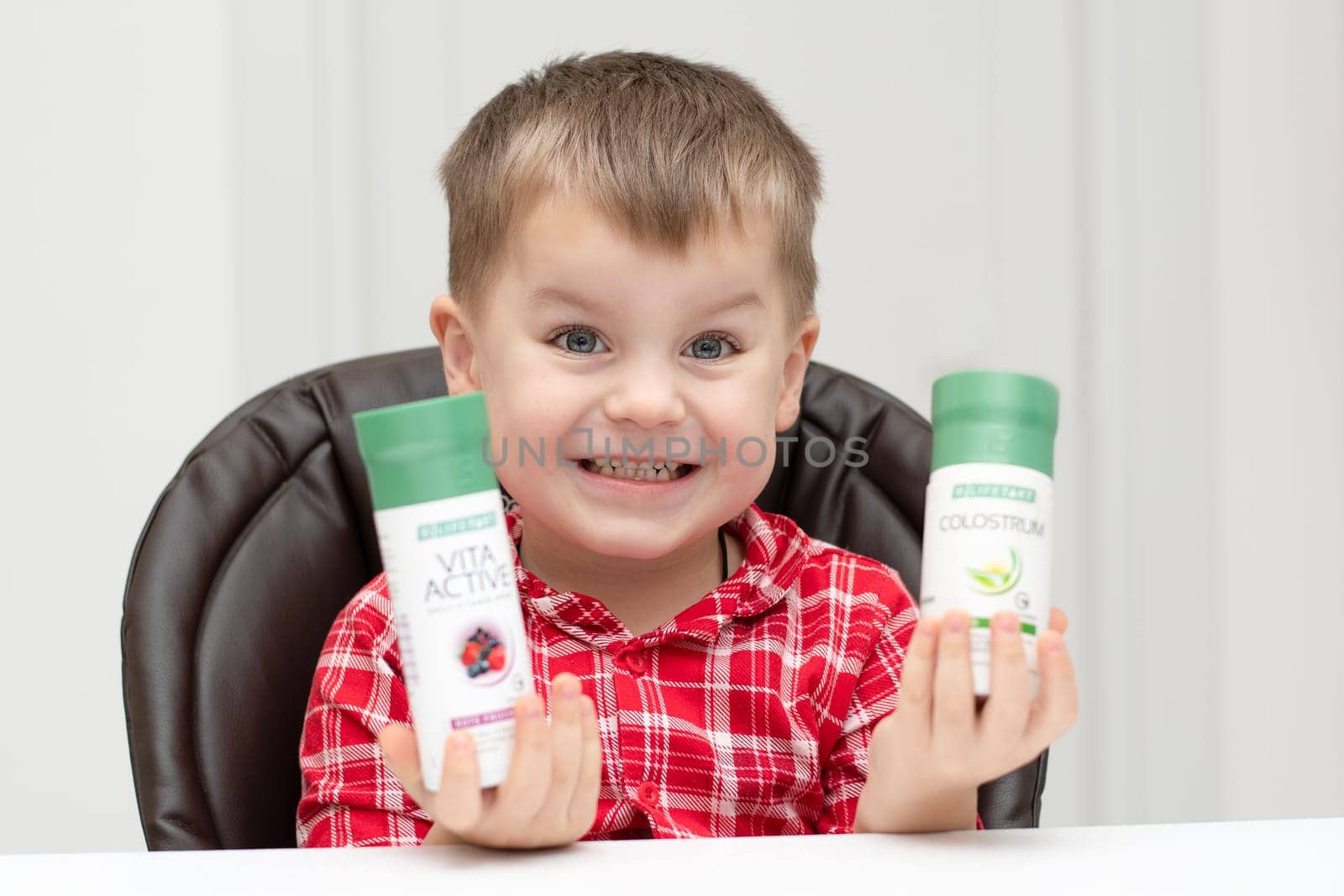 Dnepr, Ukraine - January 03,2024: a small handsome boy is sitting at a table with products from the cosmetic company LR Health and Beauty, vitamins, probiotic, colostrum. Close-up