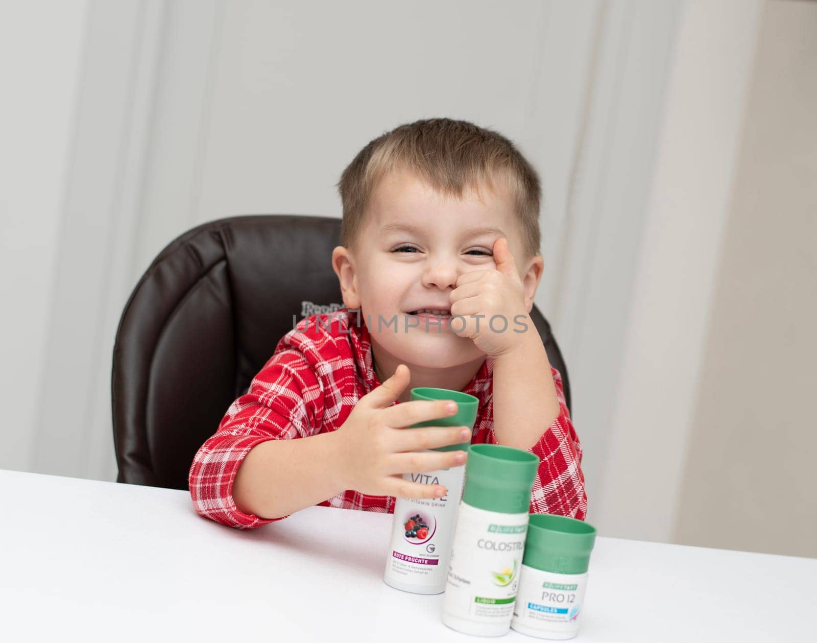 Dnepr, Ukraine - January 03,2024: a small handsome boy is sitting at a table with products from the cosmetic company LR Health and Beauty, vitamins, probiotic, colostrum. Close-up