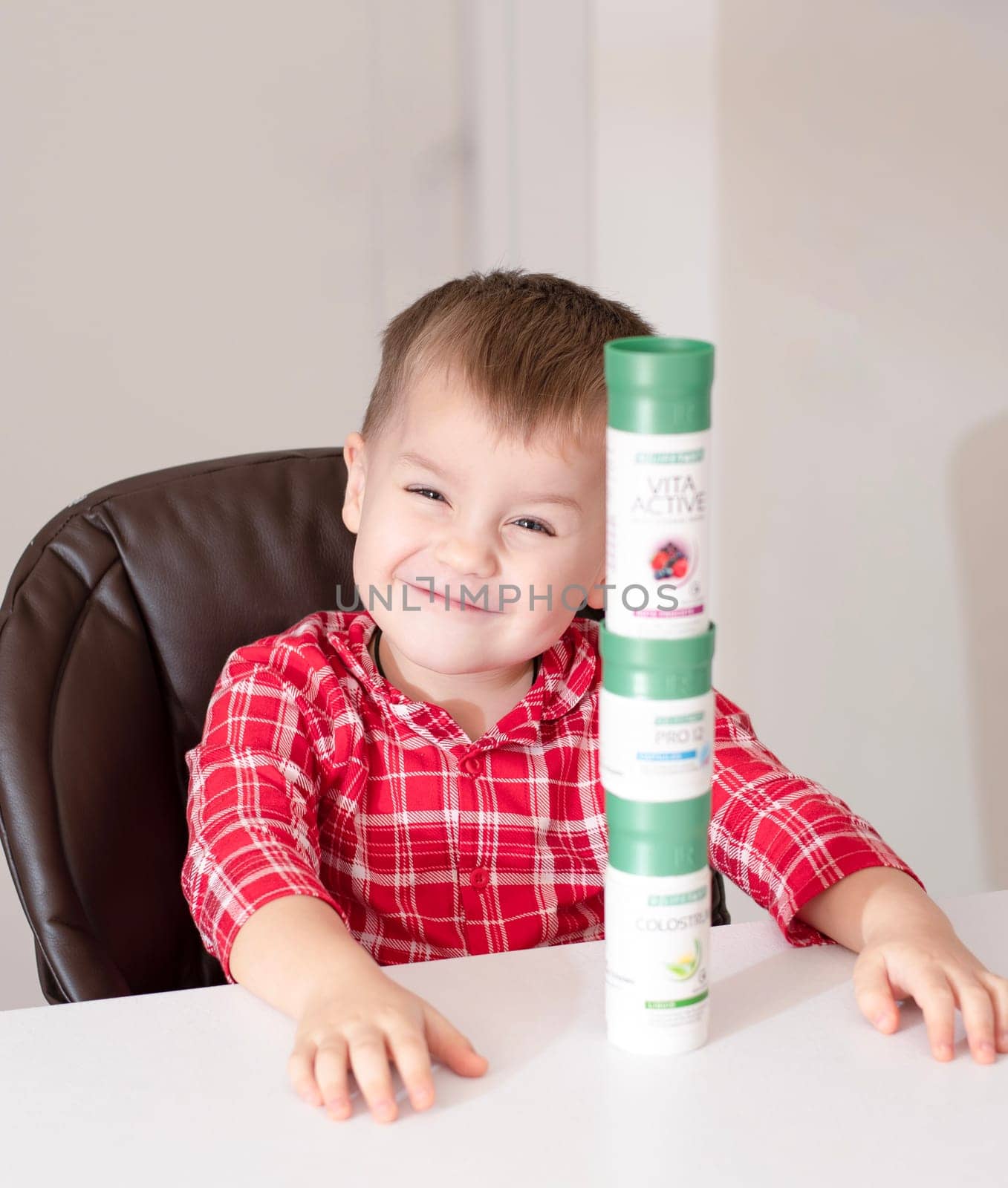 Dnepr, Ukraine - January 03,2024: a small handsome boy is sitting at a table with products from the cosmetic company LR Health and Beauty, vitamins, probiotic, colostrum. Close-up