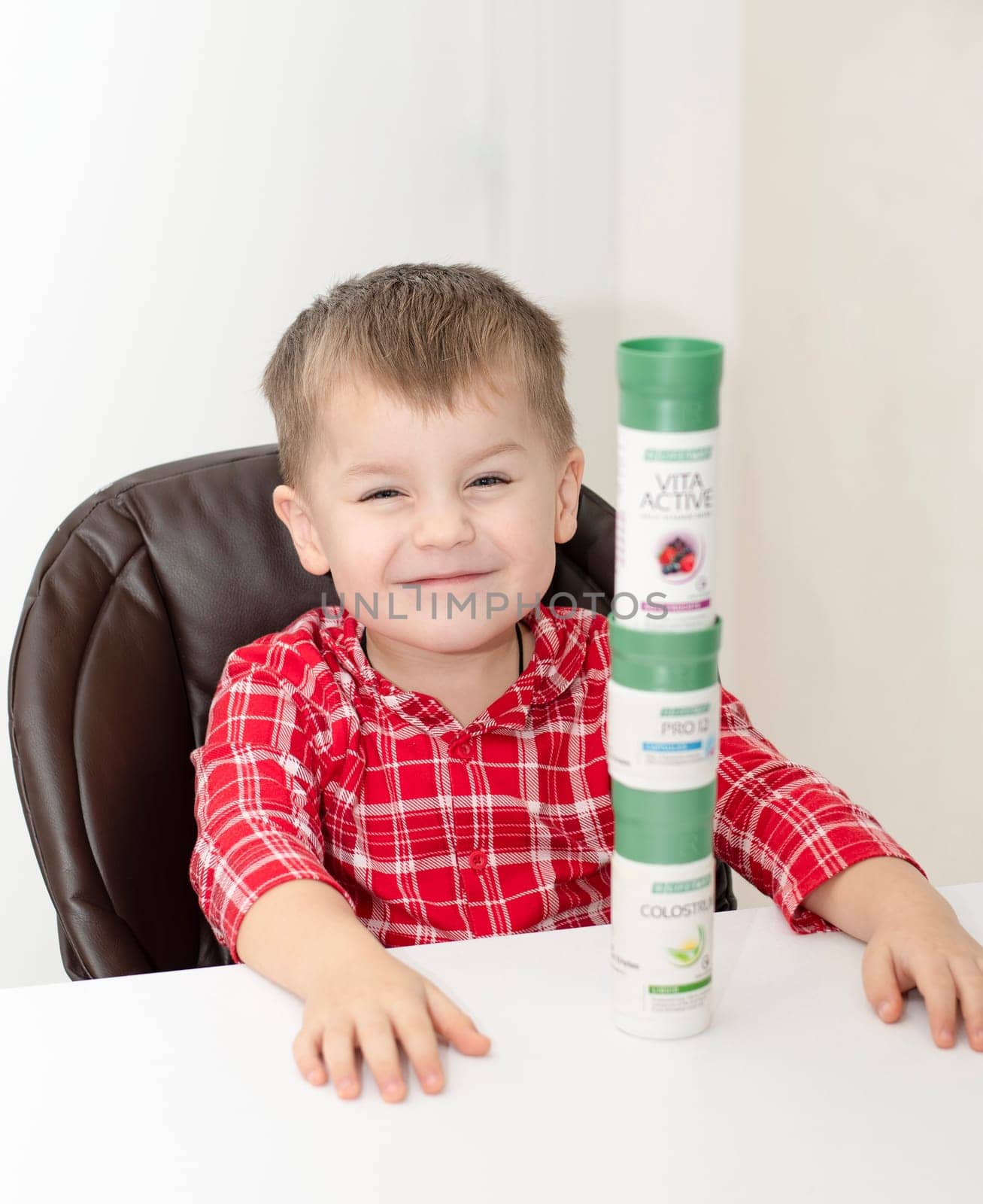 Dnepr, Ukraine - January 03,2024: a small handsome boy is sitting at a table with products from the cosmetic company LR Health and Beauty, vitamins, probiotic, colostrum. Close-up