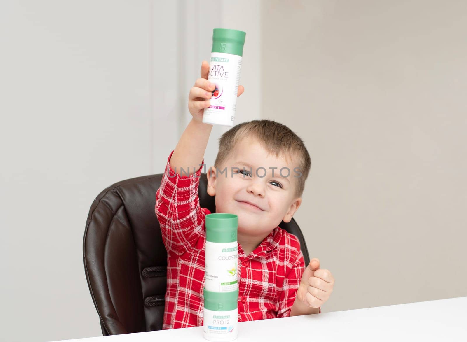 Dnepr, Ukraine - January 03,2024: a small handsome boy is sitting at a table with products from the cosmetic company LR Health and Beauty, vitamins, probiotic, colostrum. Close-up