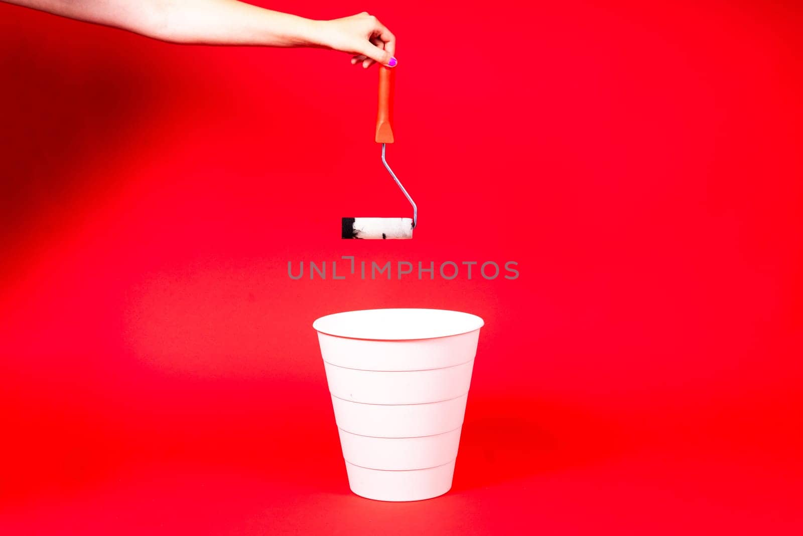 Construction roller is thrown into the trash on a red background by Zelenin