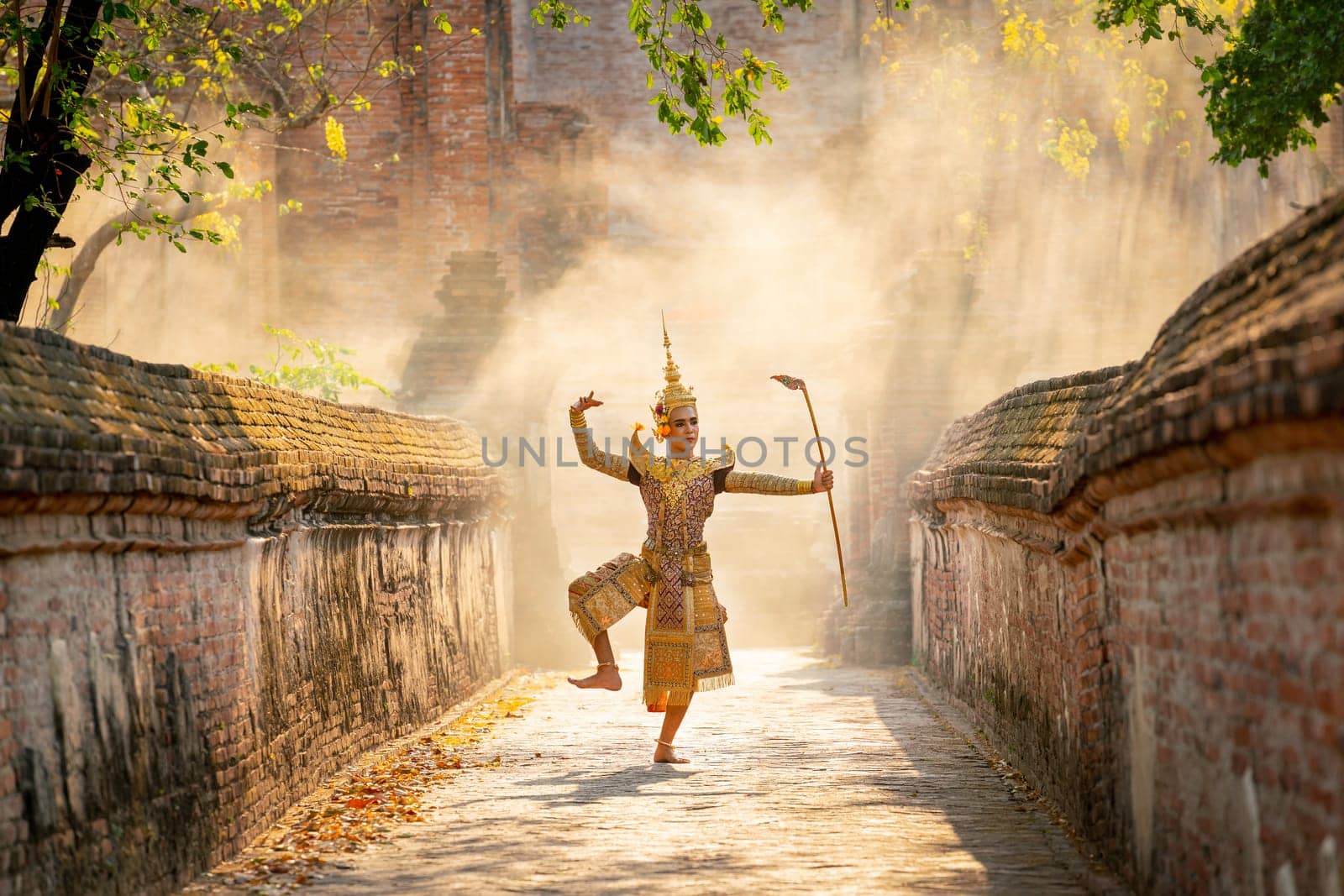 Khon or traditional Thai classic masked from the Ramakien characters as man dance in front of ancient building with tradional weapon.