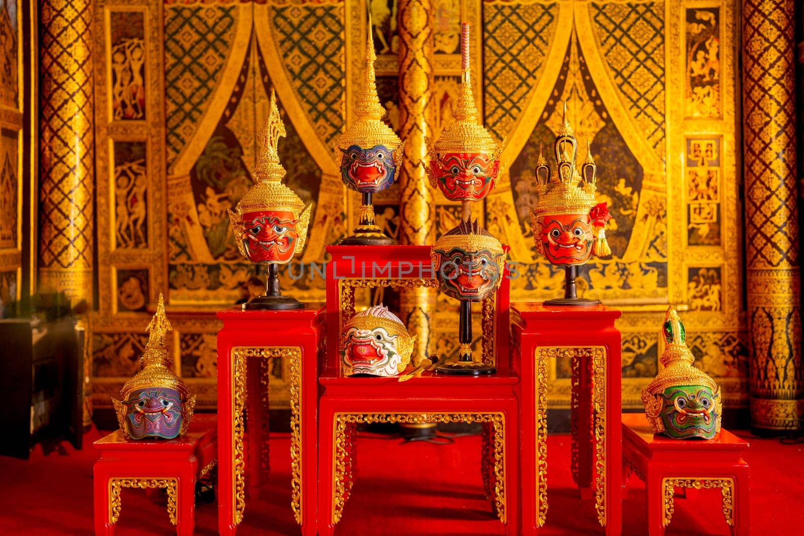 Beautiful ancient traditional Thai pattern Pantomime or Khon masks are set up on wooden shelves with Thai painting as background of public place in Thailand.