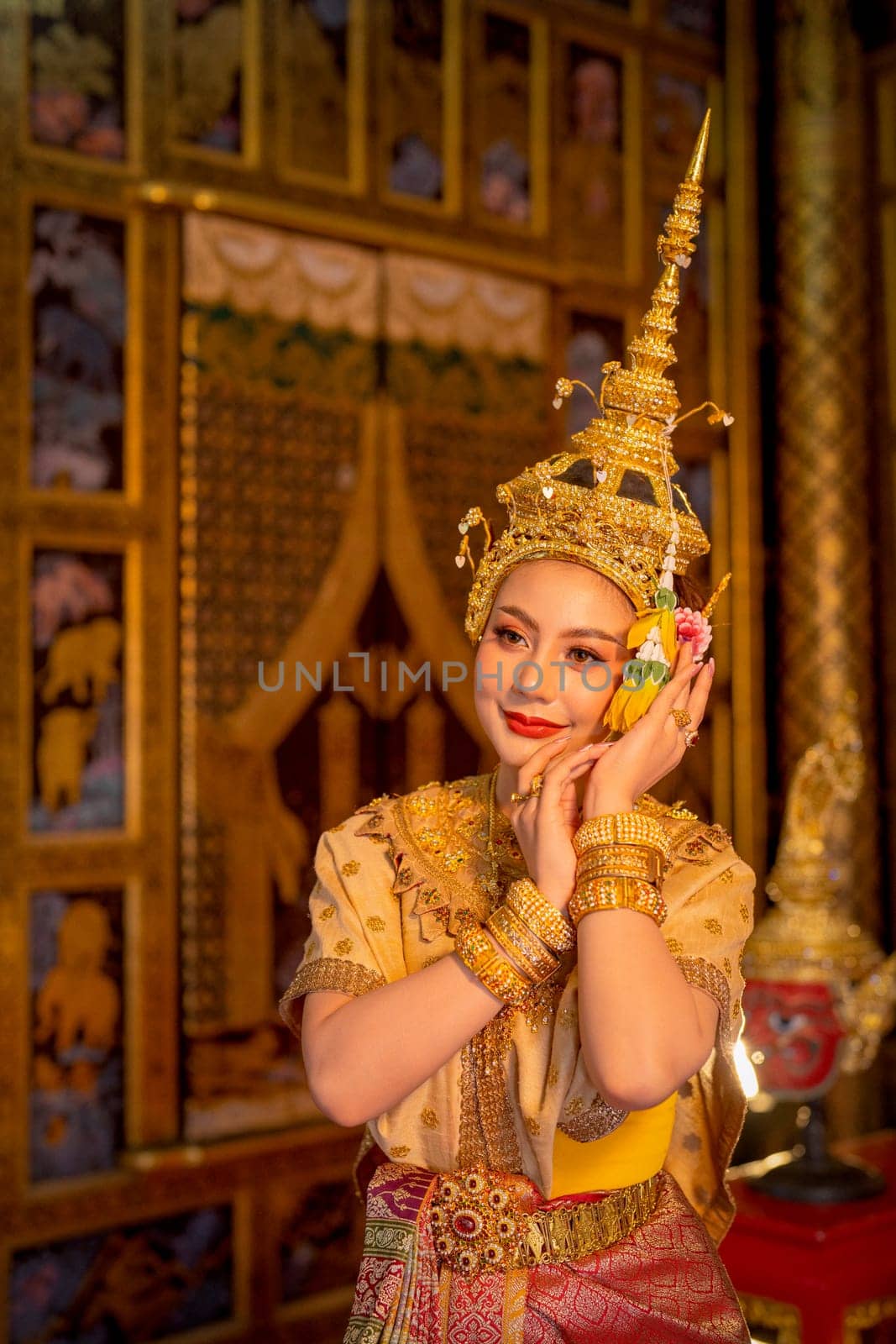 Beautiful Asian woman wear Thai ancient traditional dress action of dancing in front of Thai painting as background in public place. by nrradmin