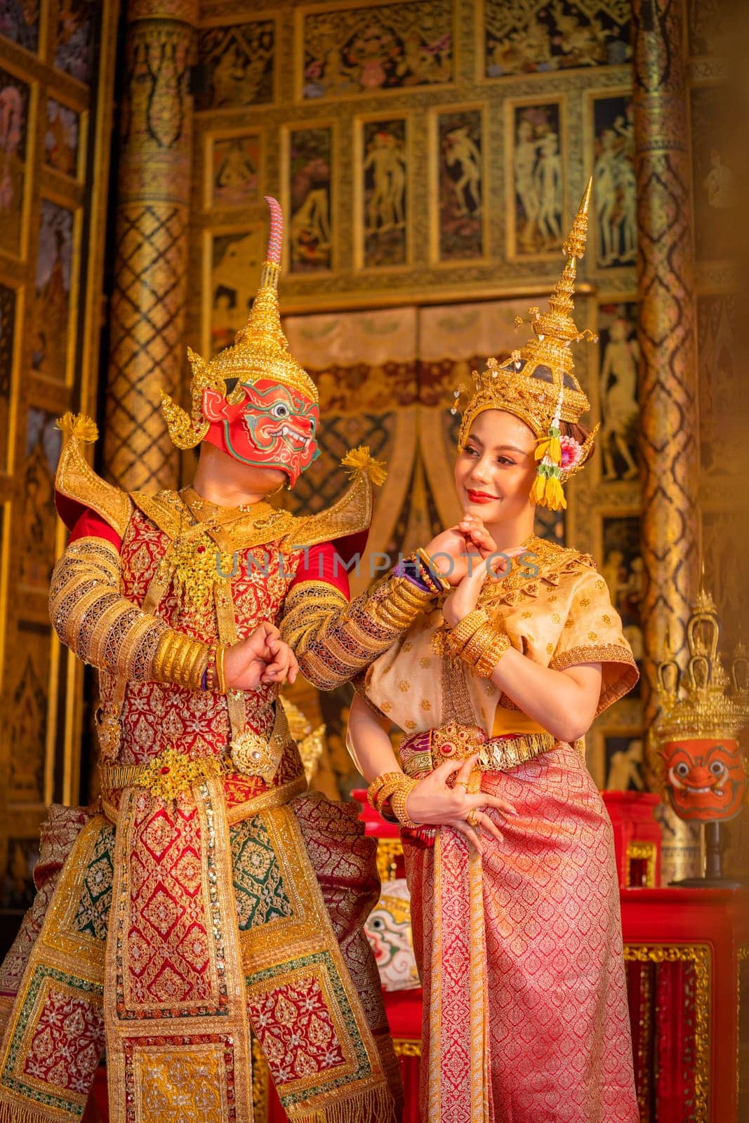 Pantomime (Khon) or traditional Thai classic masked play enacting scenes from the Ramakien (Ramayana) red giant stay with woman with a background of Thai paintings in a public place.