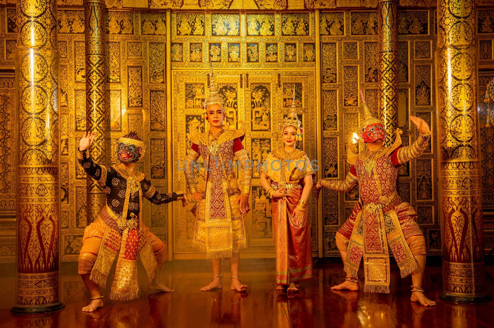 Group of Khon or traditional Thai classic masked from the Ramakien characters stand together with action of traditional dance with Thai paintings background in a public place.