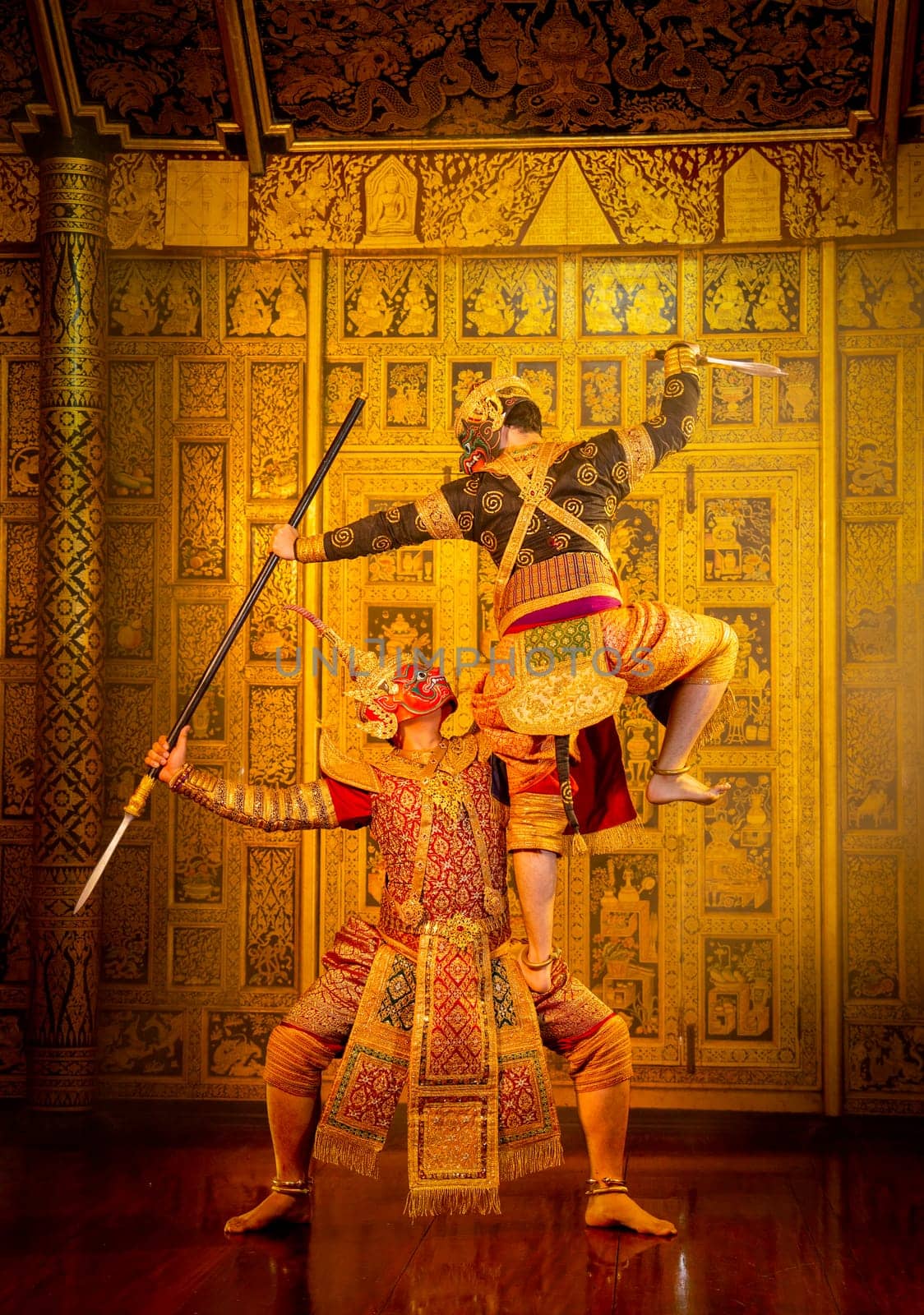 Khon or traditional Thai classic masked from the Ramakien characters action of traditional dance with fighting position and Thai painting as background in public place.