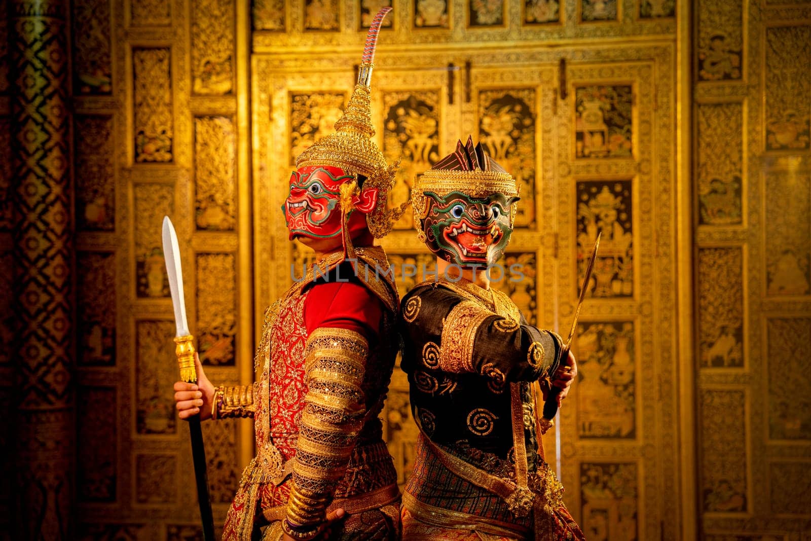 Khon or traditional Thai classic masked from the Ramakien with Red giant stand beside black monkey and Thai paintings background in a public place.