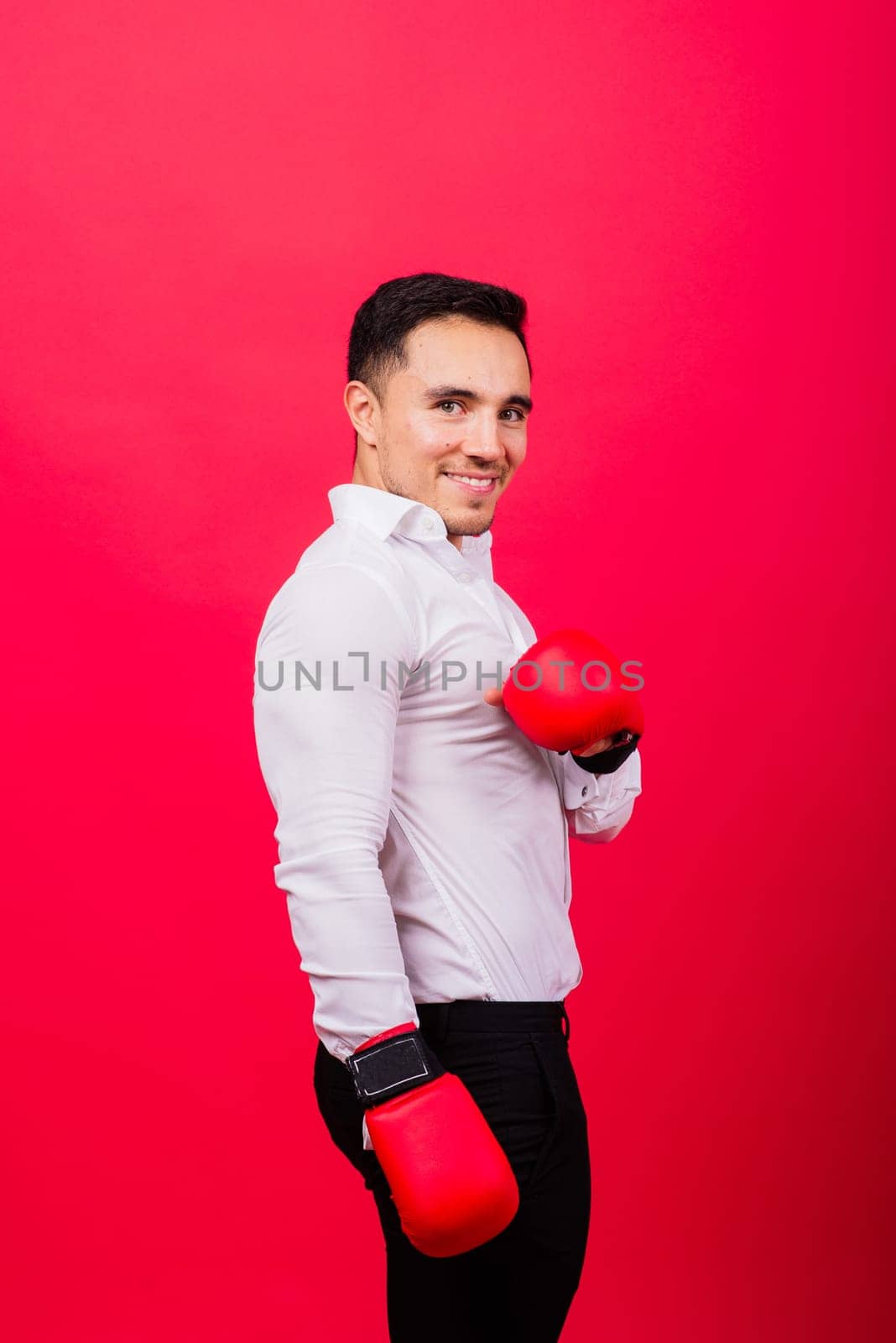 Businessman standing with boxing gloves over red background. Looking at camera by Zelenin