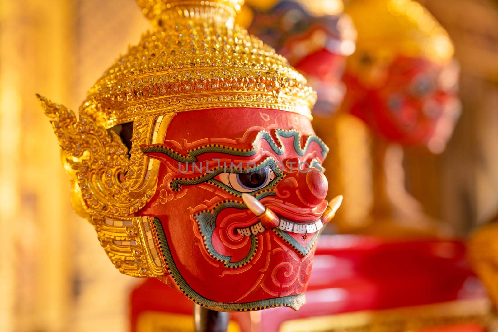 Close up beautiful ancient traditional Thai pattern Pantomime or Khon masks with main color of red are set up on wooden shelves. by nrradmin