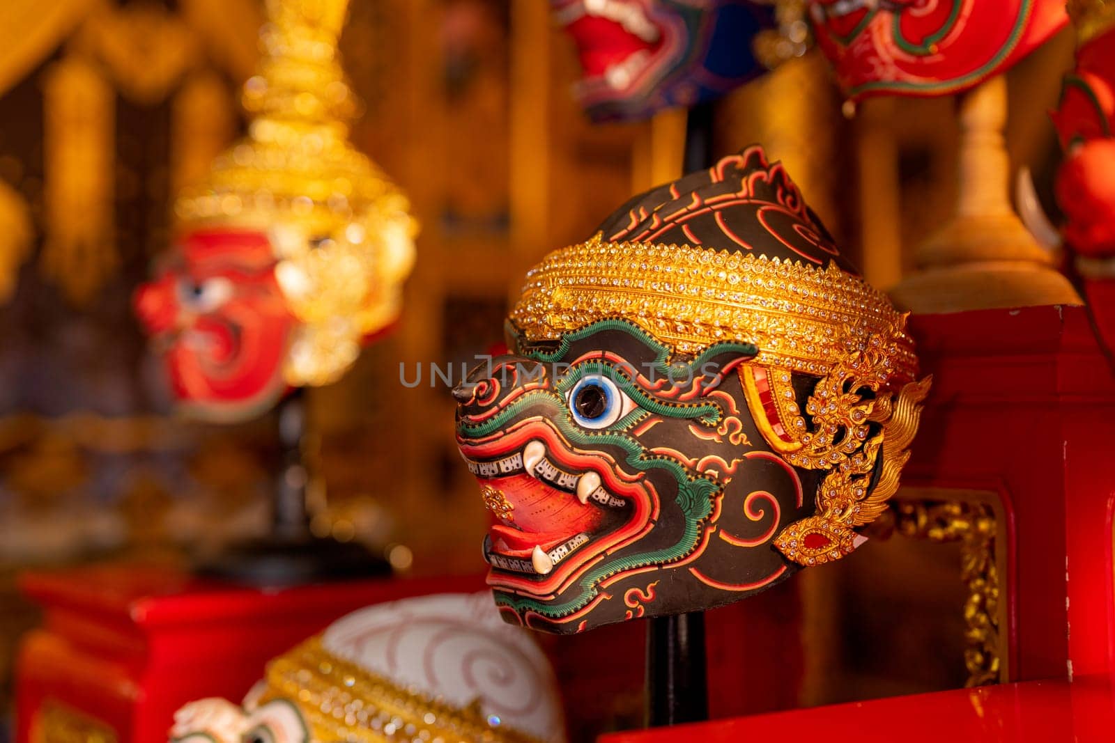Close up of beautiful ancient traditional Thai pattern Pantomime or Khon masks are set up on wooden shelves with main focus on black monkey charactor.