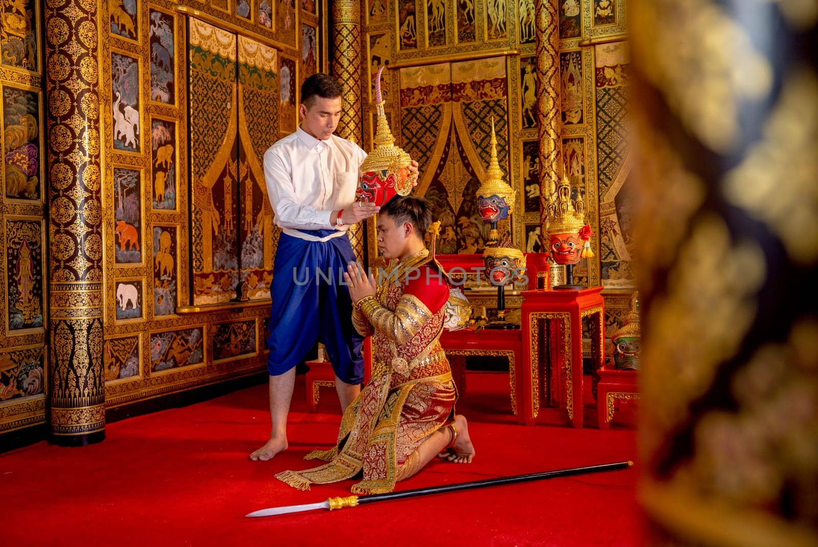 Side view of Asian man with Thai style cloth hold Khon mask and stand with action for traditional ceremony of respect to teacher.