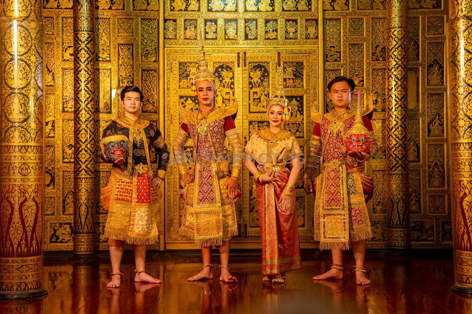 Group of Khon or traditional Thai classic masked from the Ramakien characters stand together with take the mask off also look at camera with Thai paintings background in a public place.
