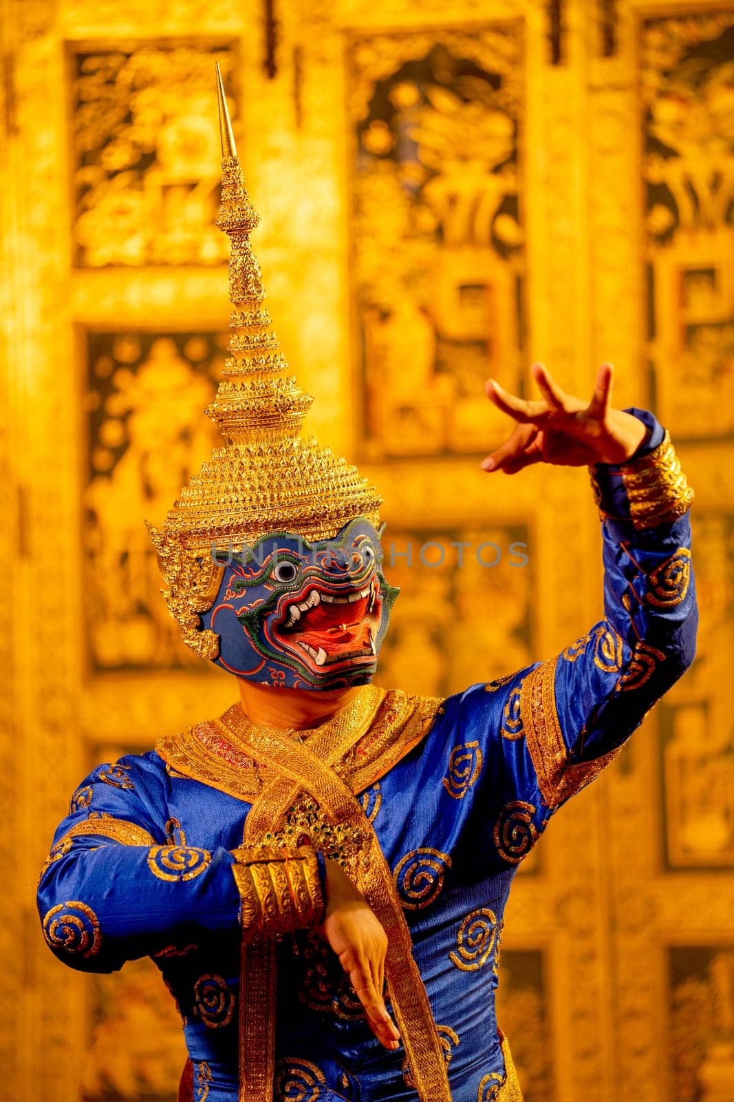 Portrait of Khon or traditional Thai classic masked from the Ramakien with character as blue giant and Thai paintings background in a public place.
