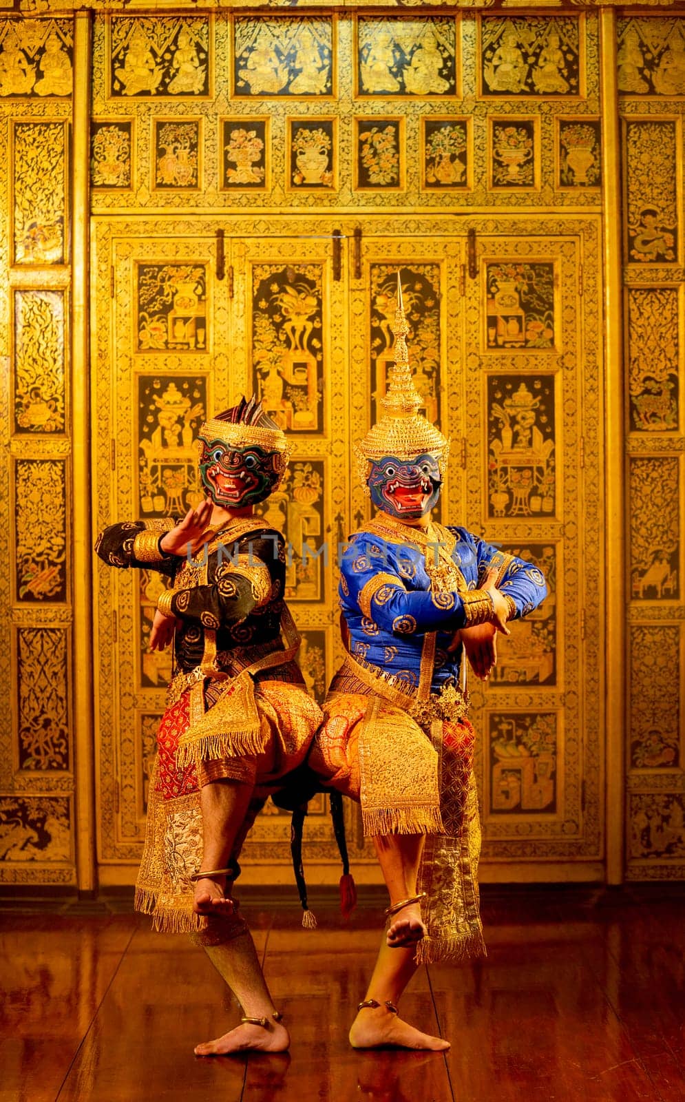 Vertical image of Khon or traditional Thai classic masked from the Ramakien with black and blue monkey stand together with action of traditional dance with Thai paintings background.