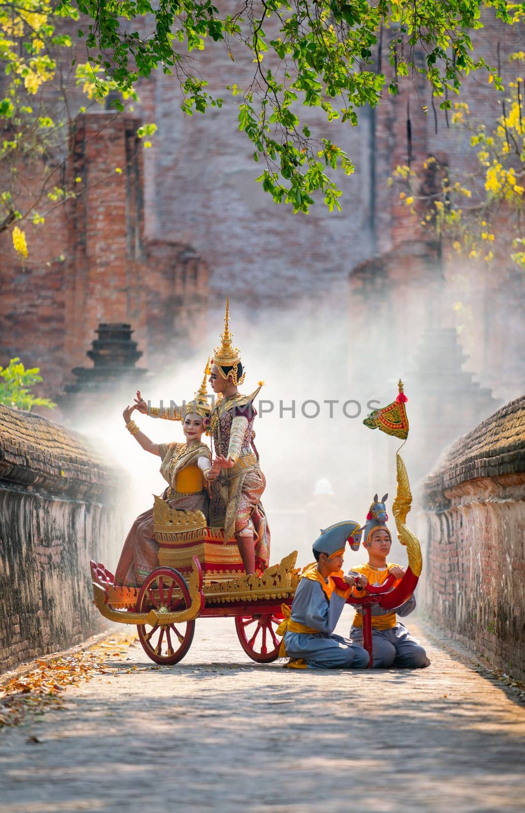 Asian man and woman with Thai old traditional dress stay together on traditional chariot in front of ancient building.