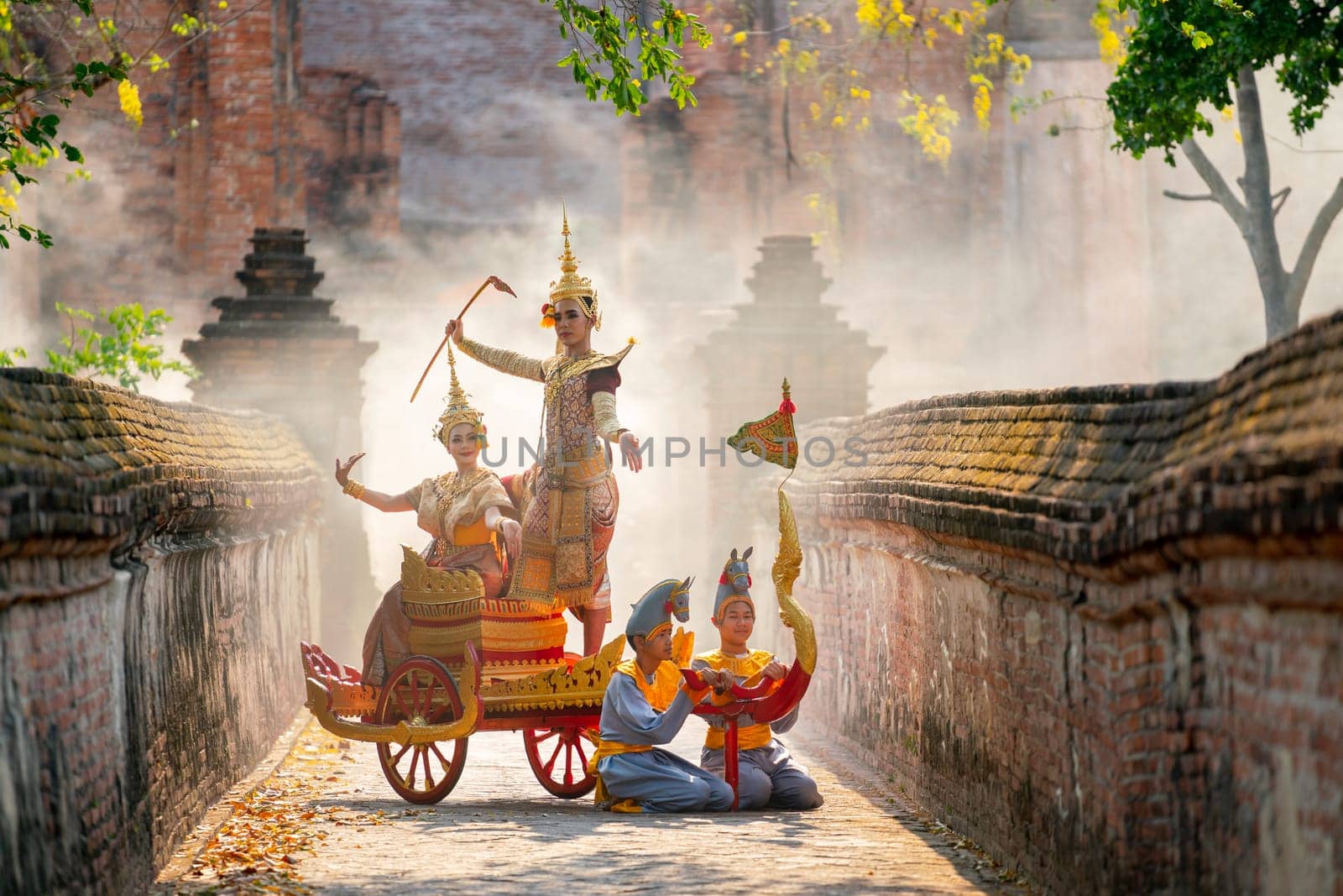 Asian man and woman with Thai old traditional dress stay together on traditional chariot in front of ancient building with mist of fog.