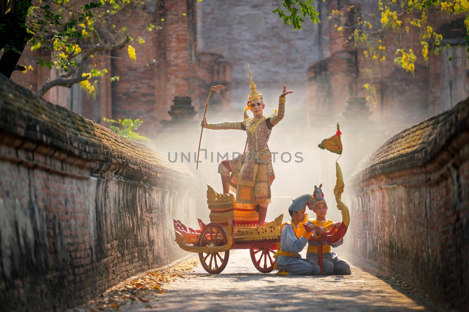 Khon or traditional Thai classic masked from the Ramakien as character of princess or king dance on traditional chariot in front of ancient building with mist or fog.