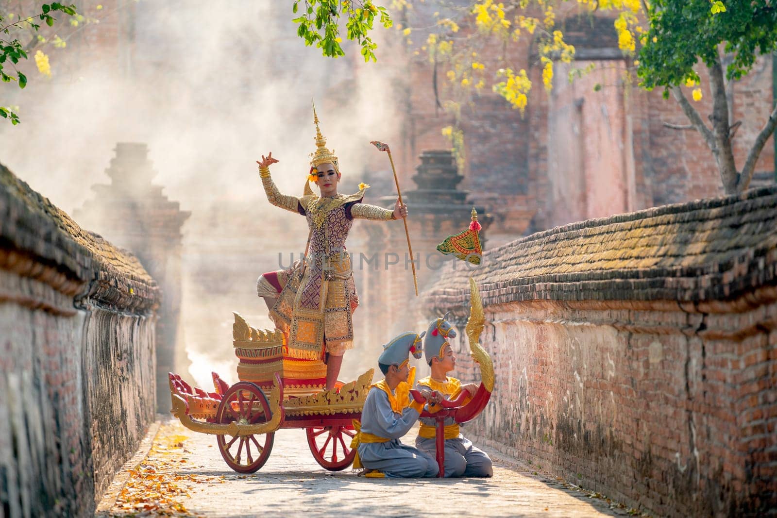 Khon or traditional Thai classic masked from the Ramakien as character of princess or king dance on traditional chariot also hold weapon stay in front of ancient building with mist or fog.