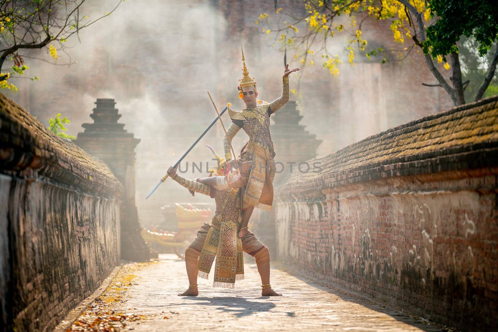 Khon or traditional Thai classic masked from the Ramakien action of traditional dance with fighting between human and giant with ancient wall and building as background in public place.