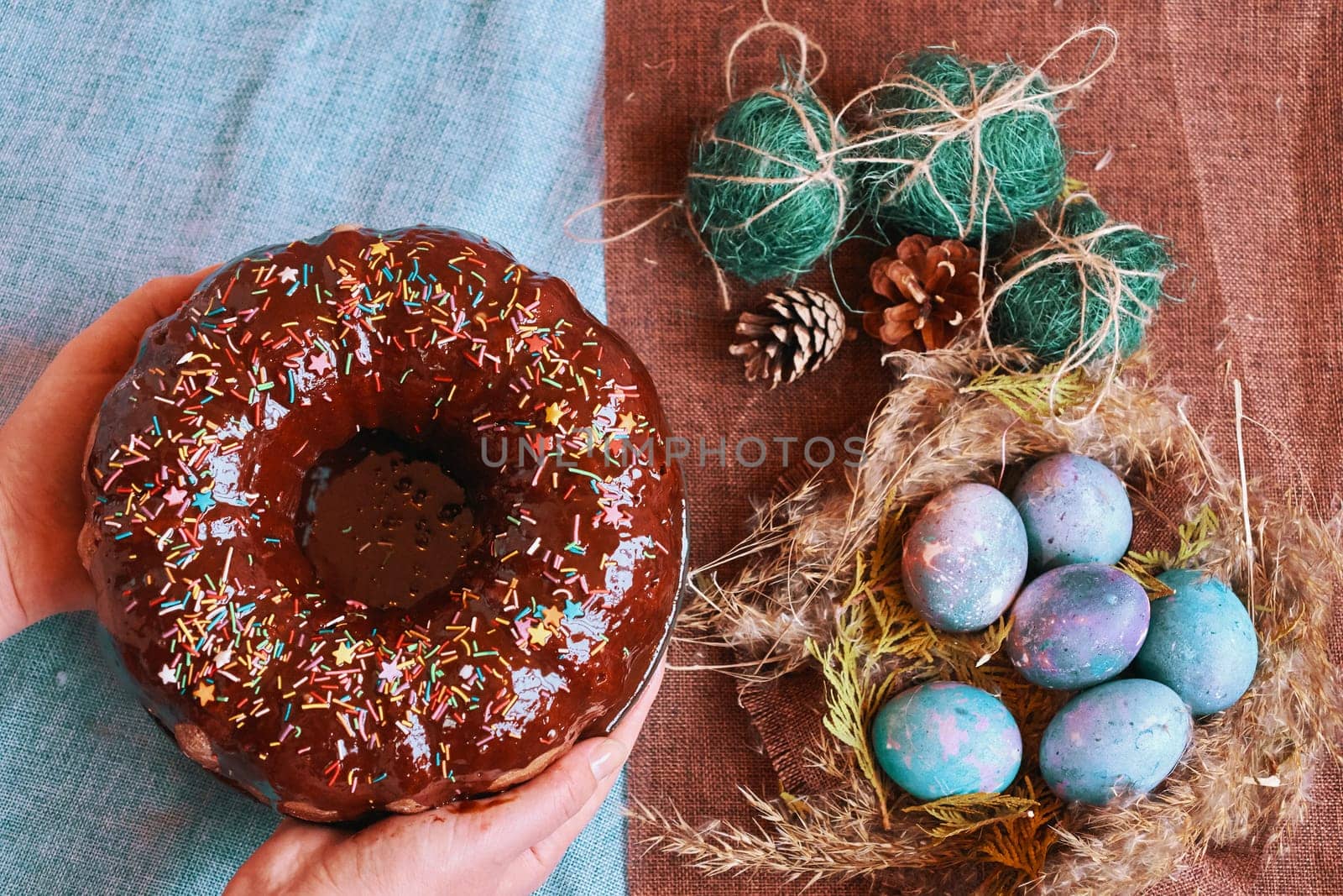 Woman holding chocolate cake with powder next to space galactic Easter eggs in nest next to bump and green filler