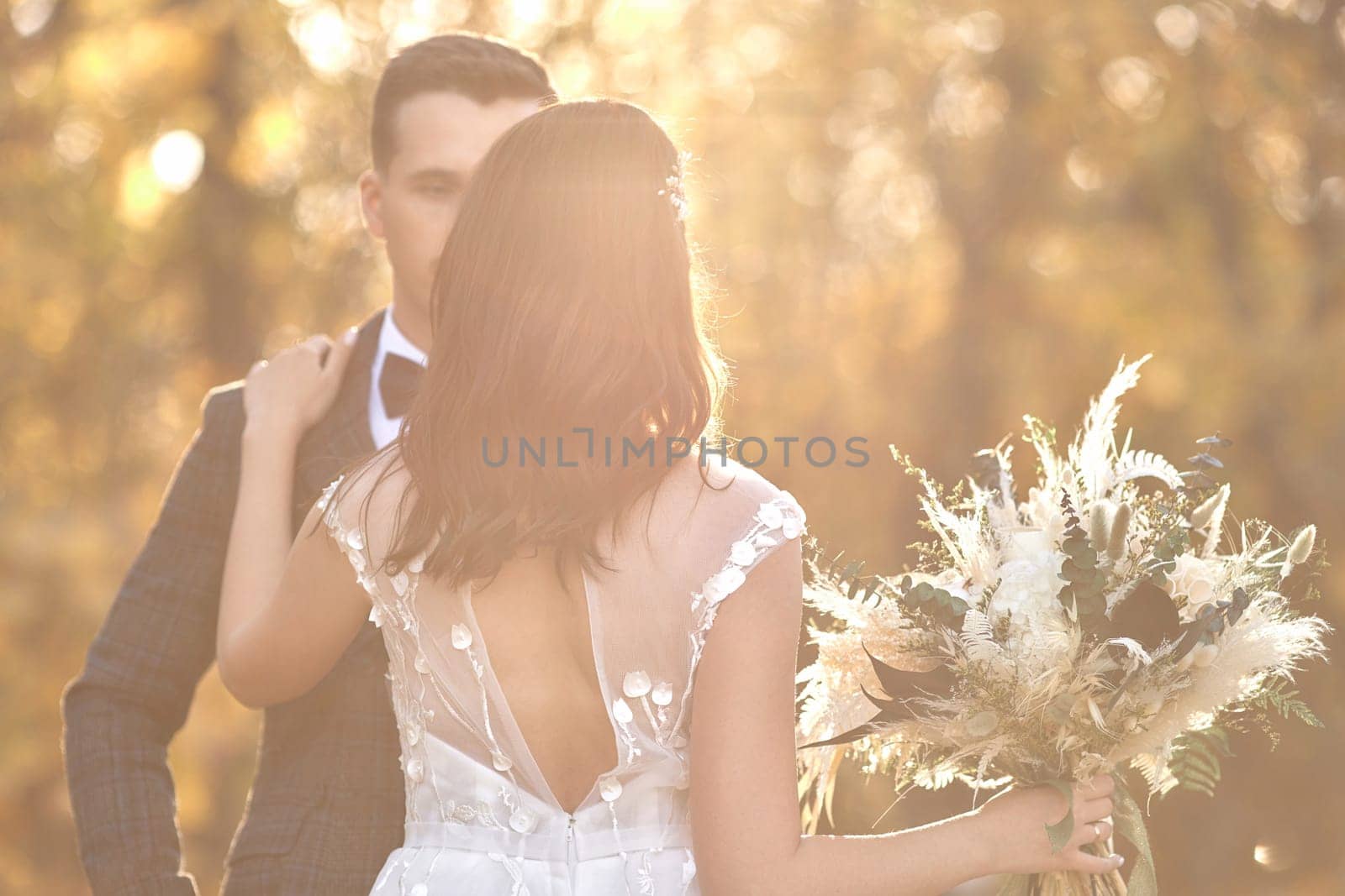 beautiful bride in white wedding dress and groom standing outdoor on natural background in sunny day. copy space