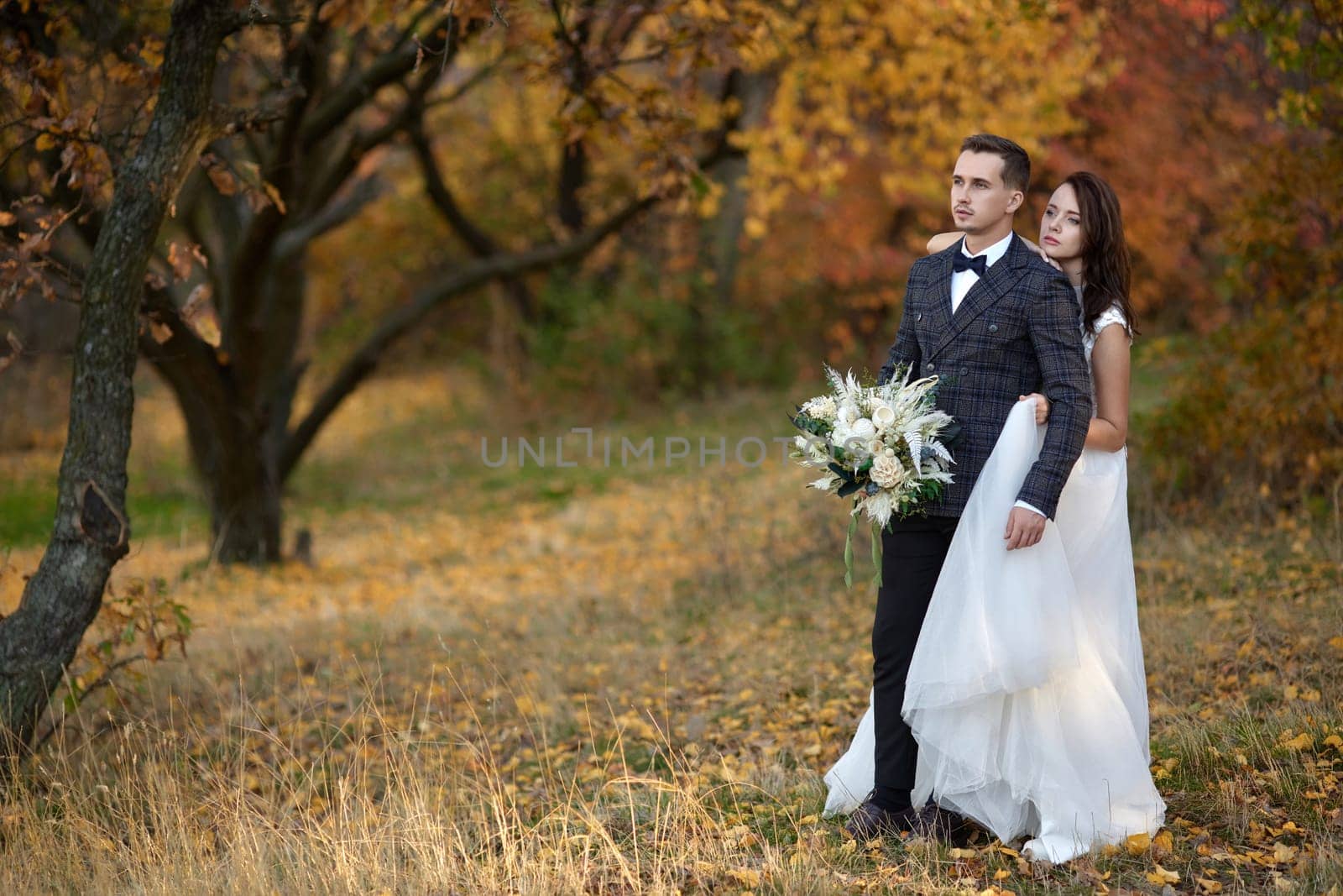 beautiful sensual bride in white wedding dress and groom standing outdoor on natural background