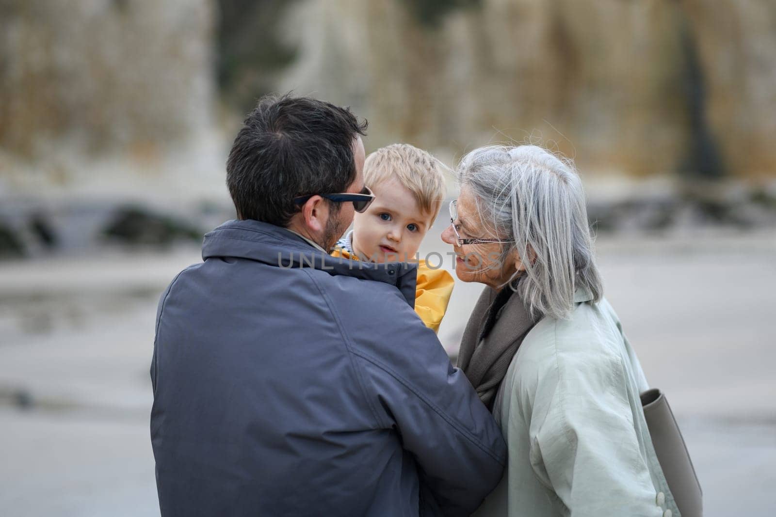 Gray-haired grandmother with a son and a grandson on a walk