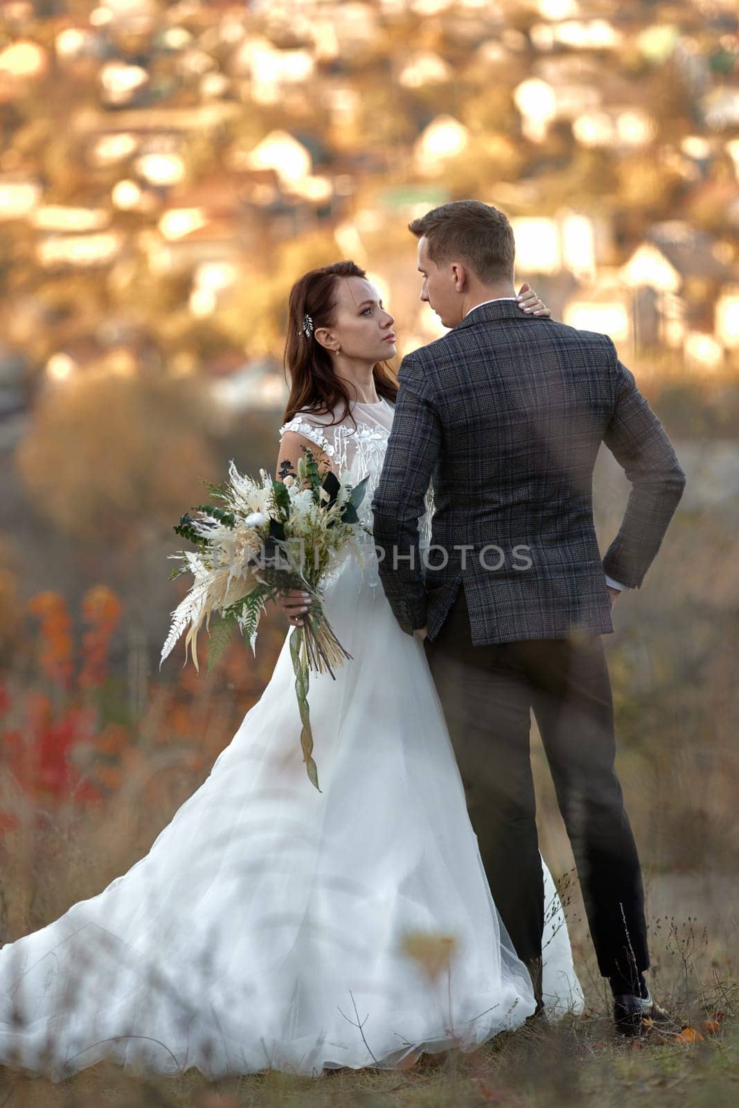 Full length body portrait of bride in white wedding dress and groom standing outdoor on natural background