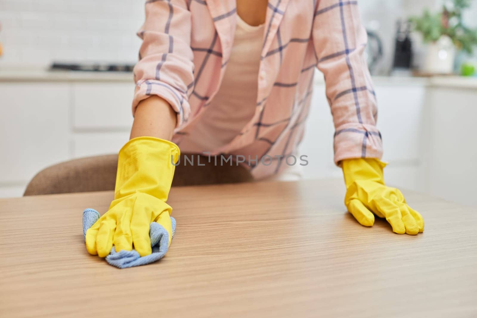 female hands cleaning and wiping wooden table with microfiber cloth. close-up. Housekeeping