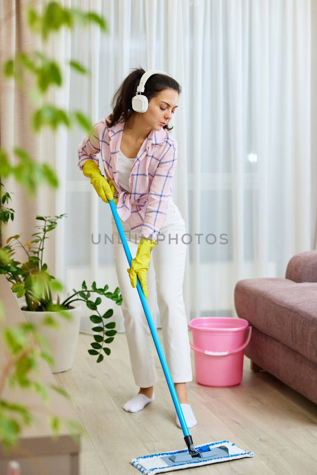 Happy woman singing and washing floor at living room, house chores.