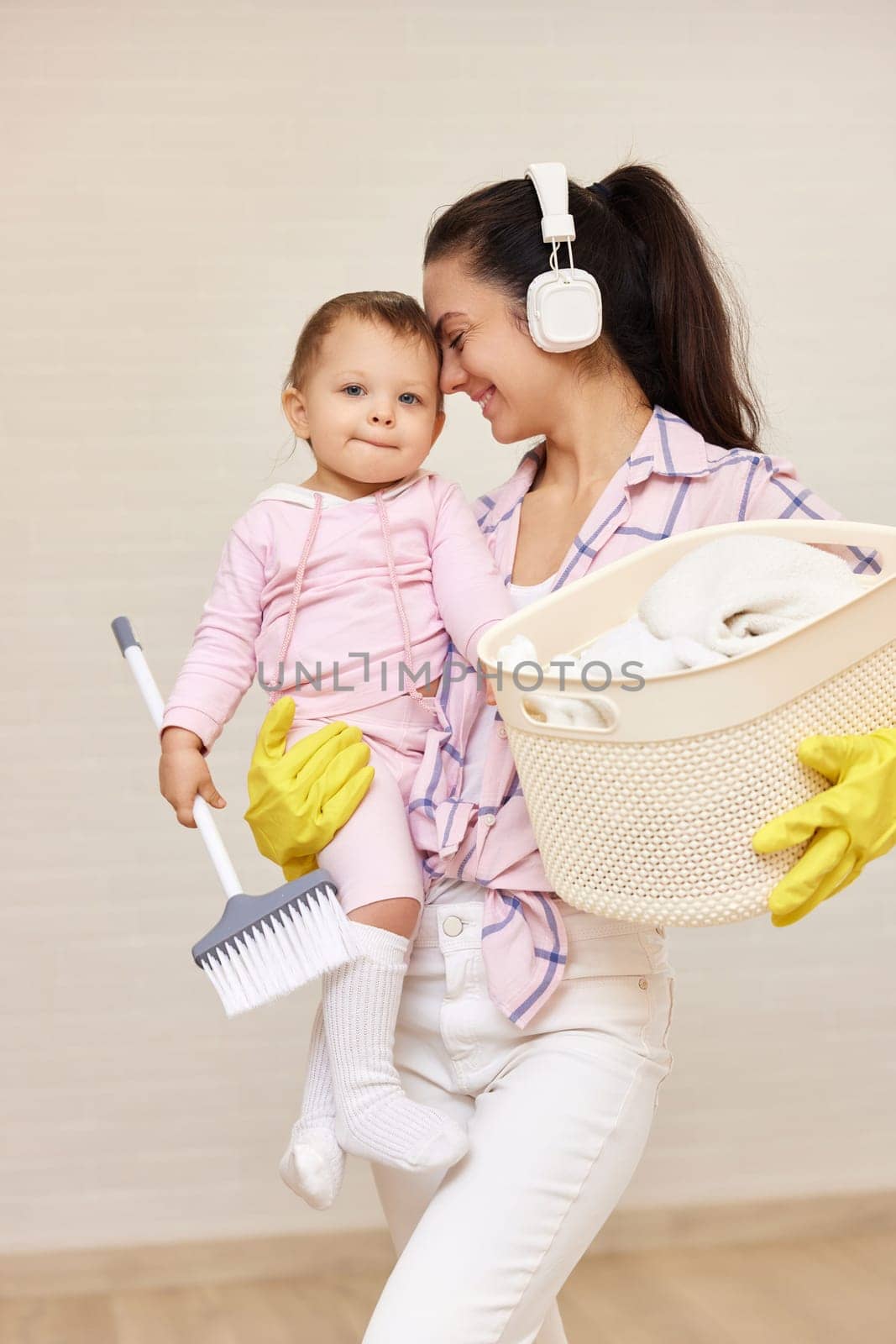 happy mother housewife is holding cute little child girl and basket with laundry and doing housework , Happy family