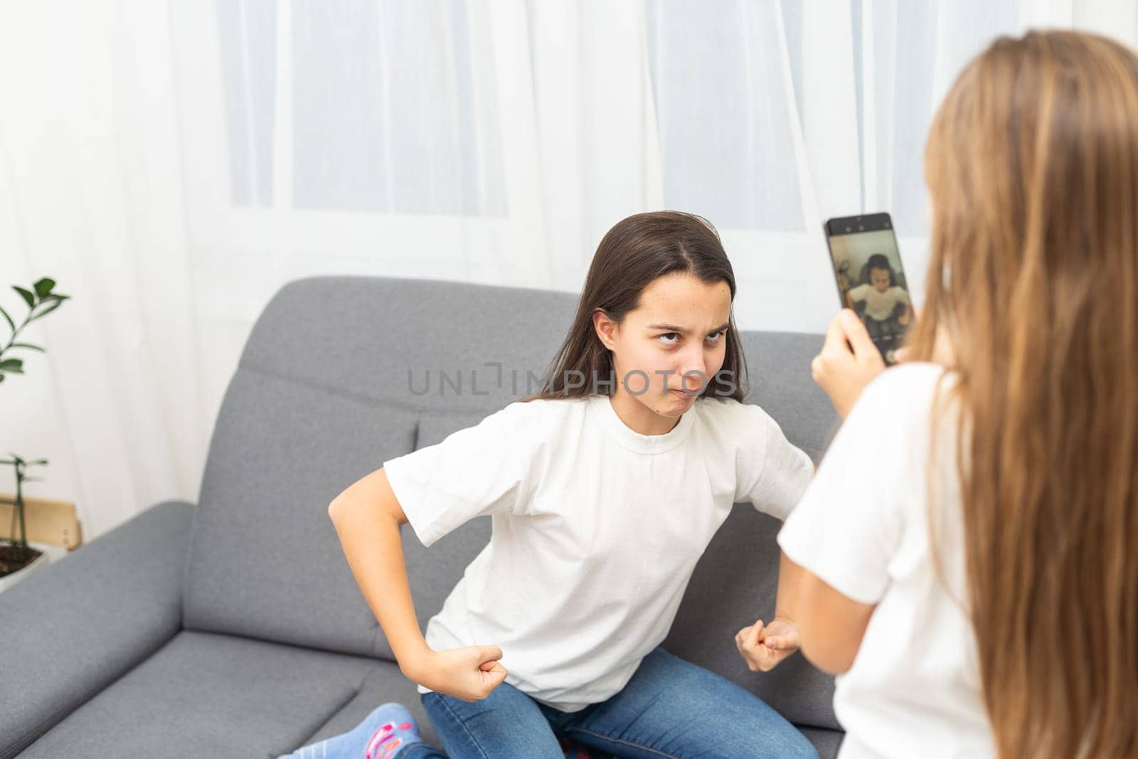 people, technology and friendship concept - happy teenage girls taking selfie with smartphone sitting on sofa at home. High quality photo