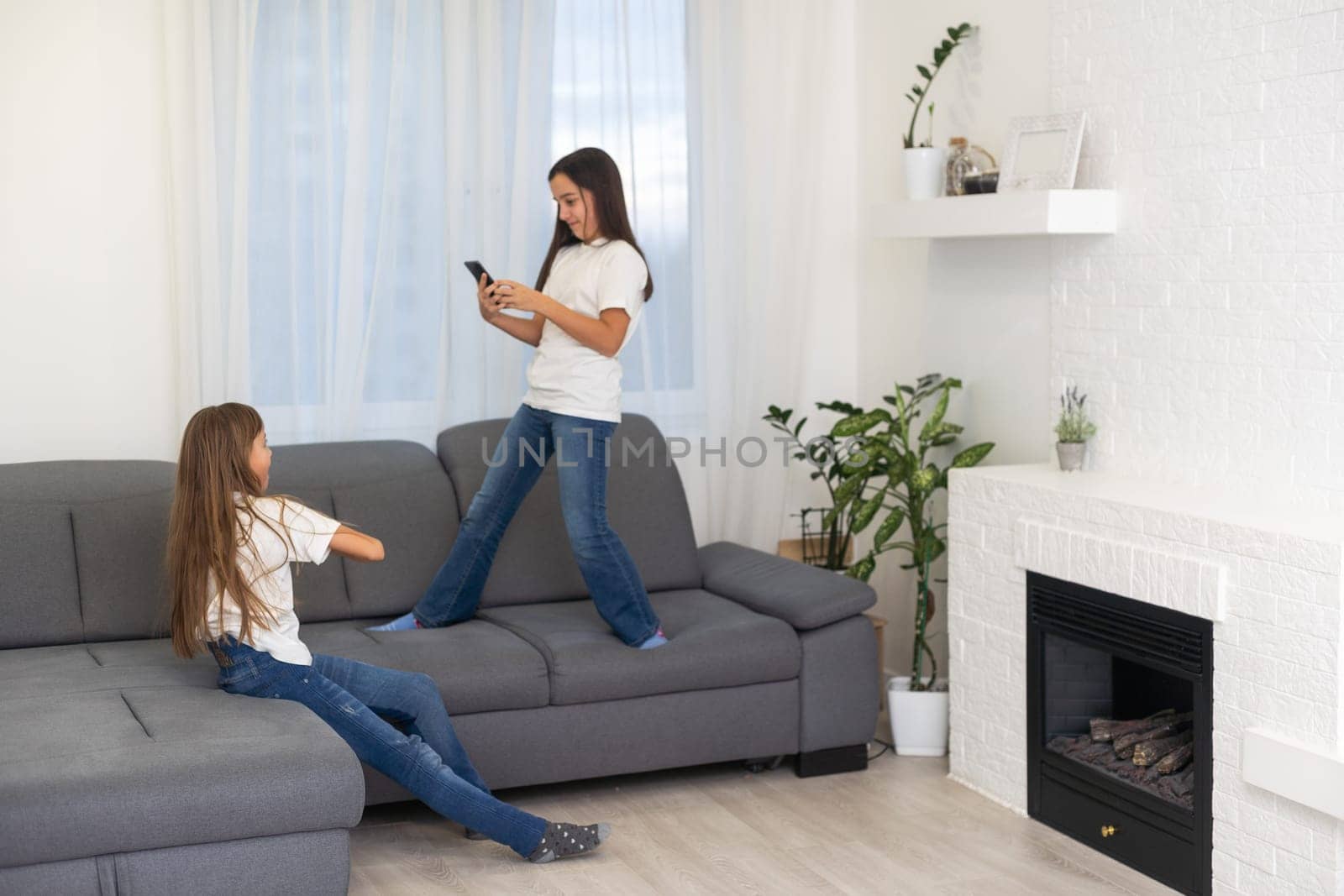 Two cute Caucasian blonde girls sisters holding cell phone and laughing. High quality photo