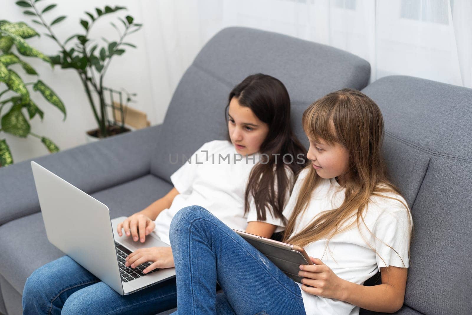 people, children, technology, friends and friendship concept - girls looking to tablet pc computers at home. High quality photo